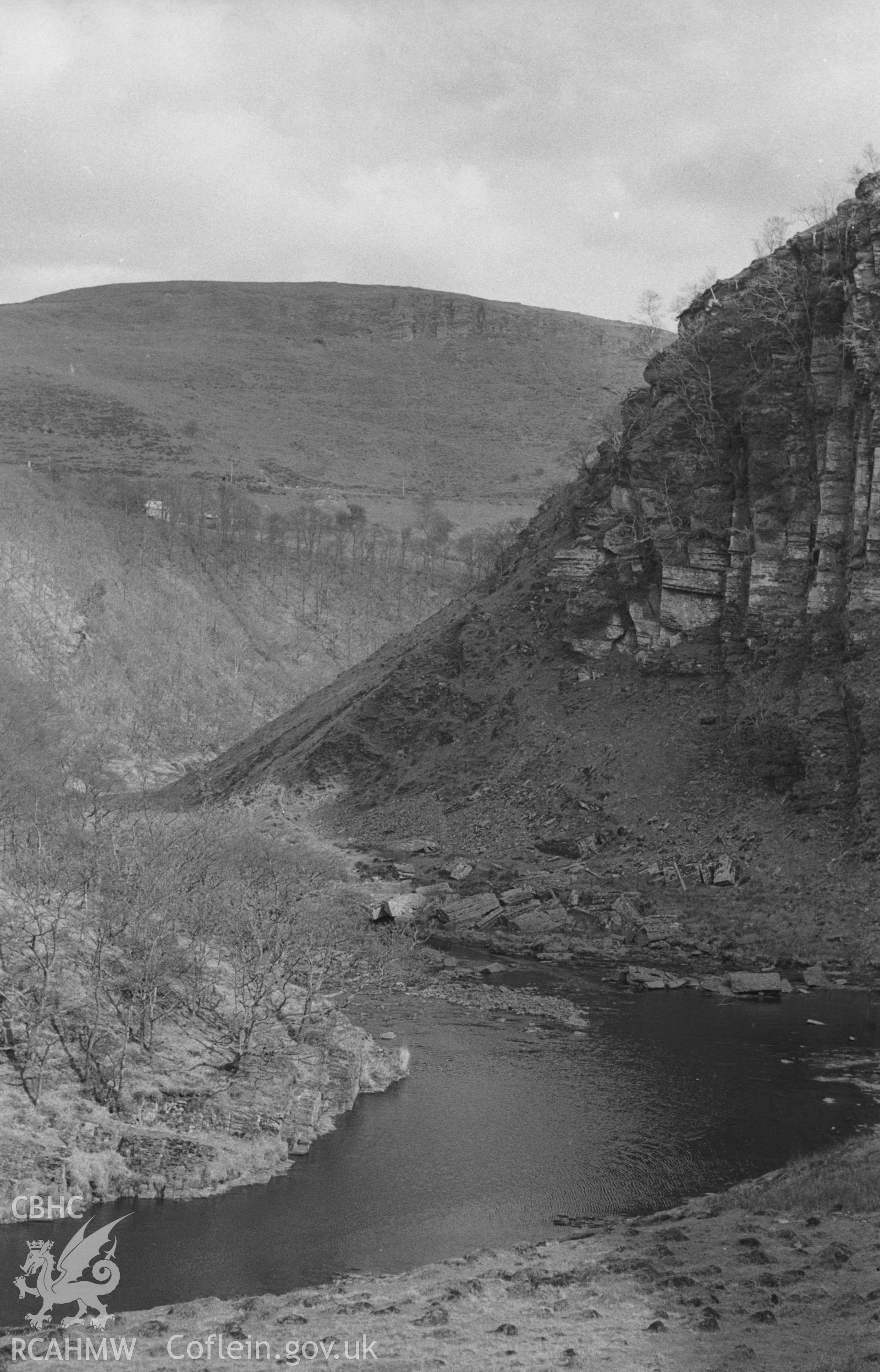 Digital copy of black & white negative showing view looking down the Rheidol to cliffs at north side of Bryn Bras; Ty'n y Ffordd on road below Mynydd yr Ychen in distance. Photographed in April 1964 by Arthur O. Chater, SN 7505 7987, looking south east.