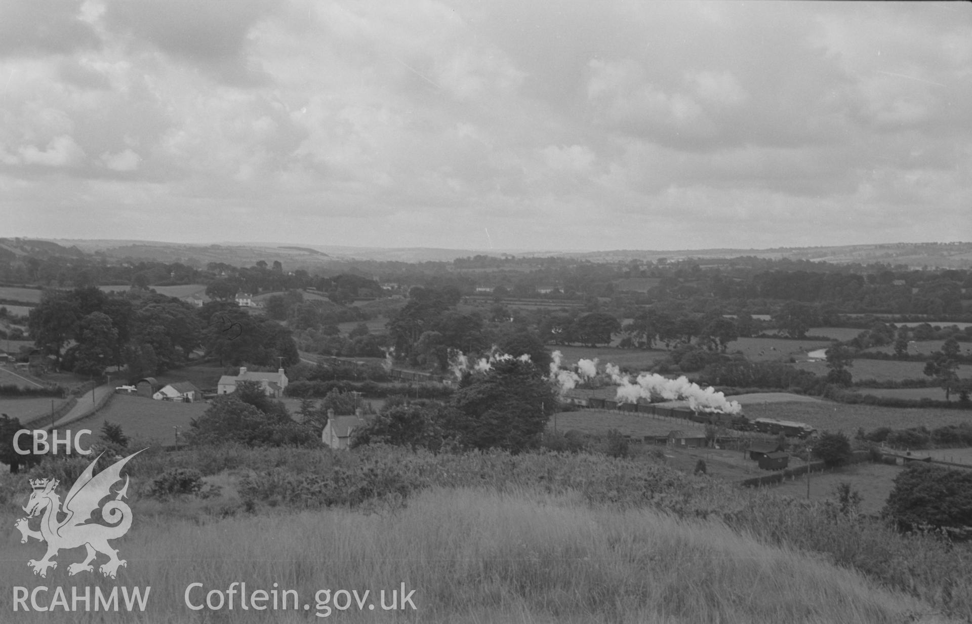 Digital copy of black & white negative showing view from outside Pencarreg churchyard (SN 535 450) looking west south west down Teifi valley at diesel train on Lampeter - Carmarthen line with steam engine attached. Photograph by Arthur Chater, Sept 1963.