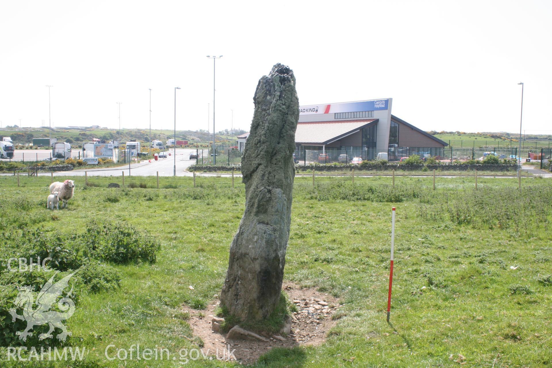 View of Ty-Mawr Standing Stone, from the southwest. Looking across A5 carriageway towards retail units. Digital photograph taken for archaeological work at Parc Cybi Enterprise Zone, Holyhead, carried out by Archaeology Wales, 2017. Project no: P2522.