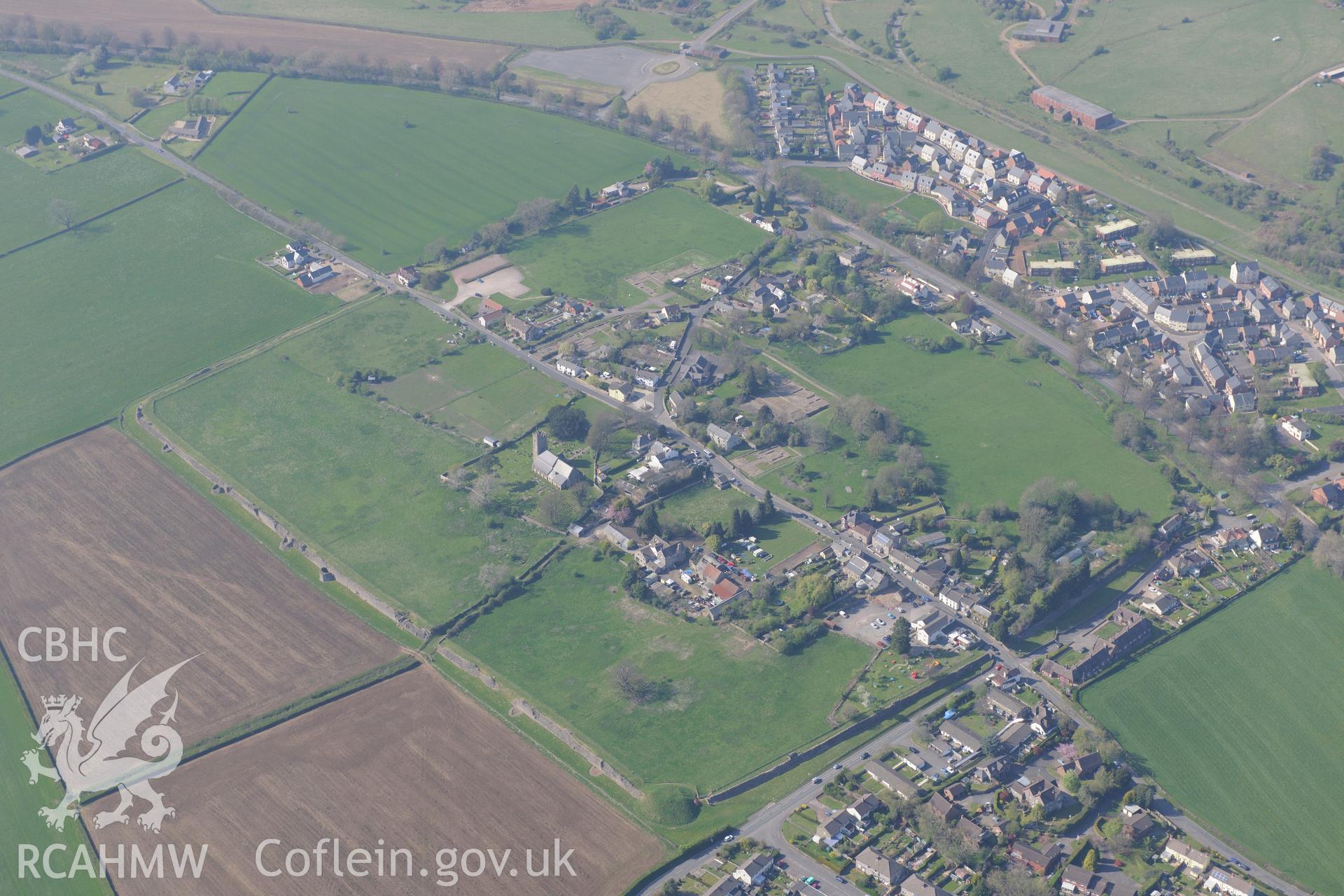 Caerwent village and Roman city including views of the Roman Amphitheatre and Basilica and Forum; St. Stephen's Church; Caerwent House; Great House and West Gate Farm. Oblique aerial photograph taken during the Royal Commission's programme of archaeological aerial reconnaissance by Toby Driver on 21st April 2015.