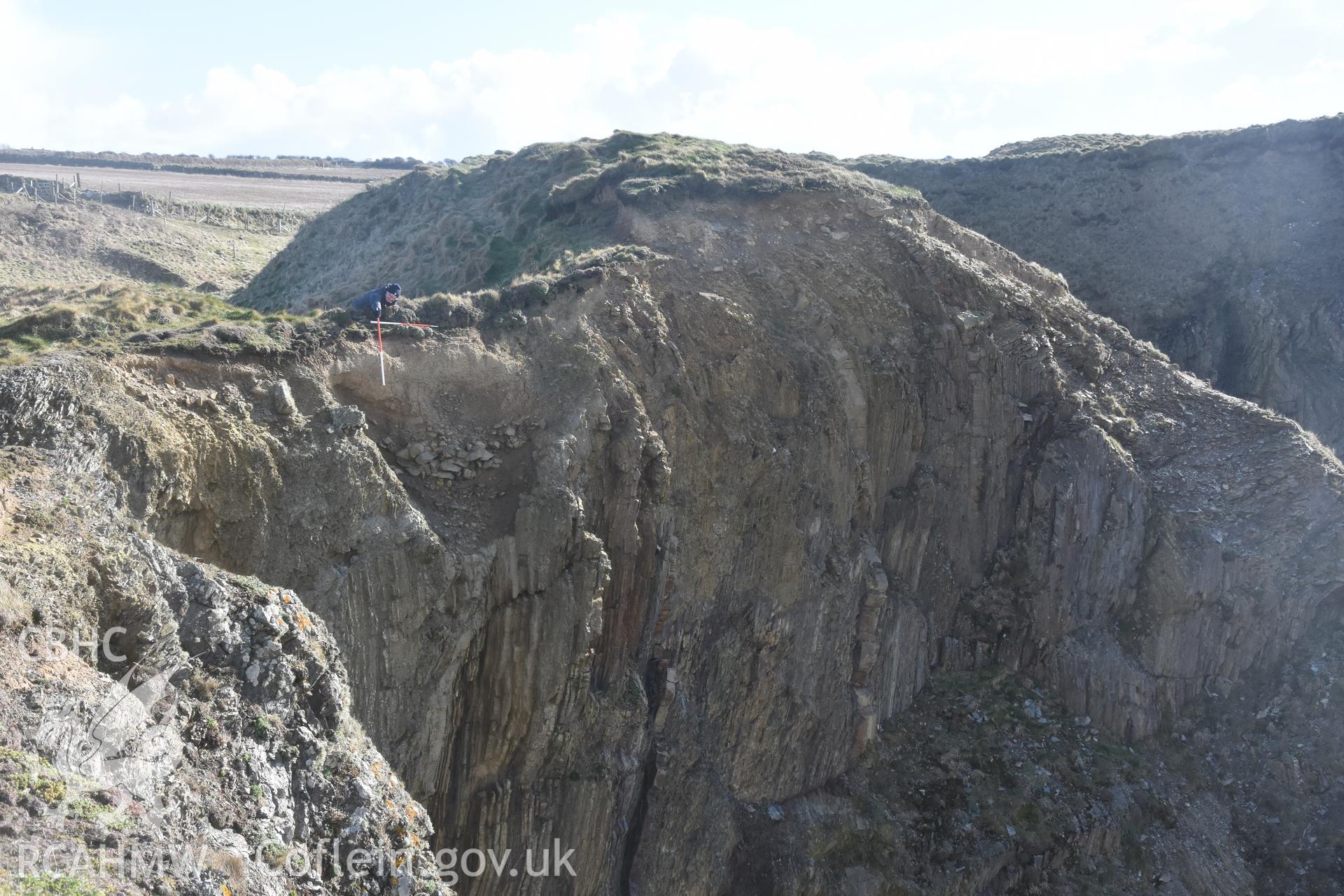 Porth y Rhaw promontory fort. Photograph of eroded section through western rock-cut ditch. ? Crown: CHERISH PROJECT 2017. Produced with EU funds through the Ireland Wales Co-operation Programme 2014-2020. All material made freely available through the Open Government Licence.