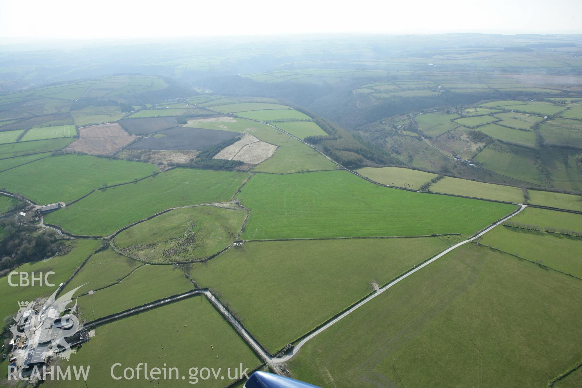 RCAHMW colour oblique aerial photograph of Crug Gwyn. A wide landscape view with Crug Gwyn and Crug Bach. Taken on 13 April 2010 by Toby Driver