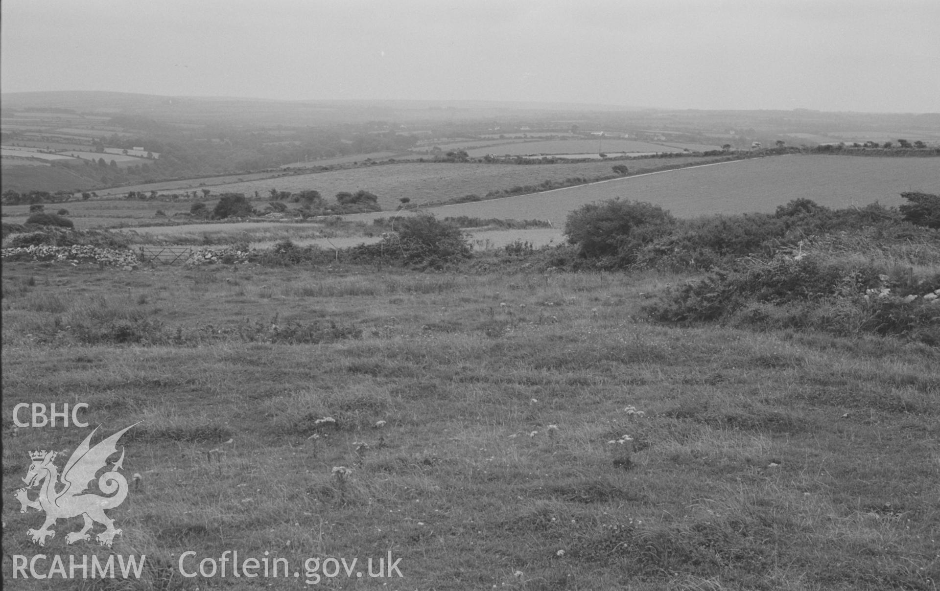 Digital copy of a black and white negative showing the circular, partly ploughed-out bank of Gaer-Wen pre-Roman Iron Age farmstead, 4km north east of Llangrannog. Gaer Wern Farm on he left, 575ft. Photographed by Arthur O. Chater in August 1967. (Looking south east from Grid Reference SN 345 564).