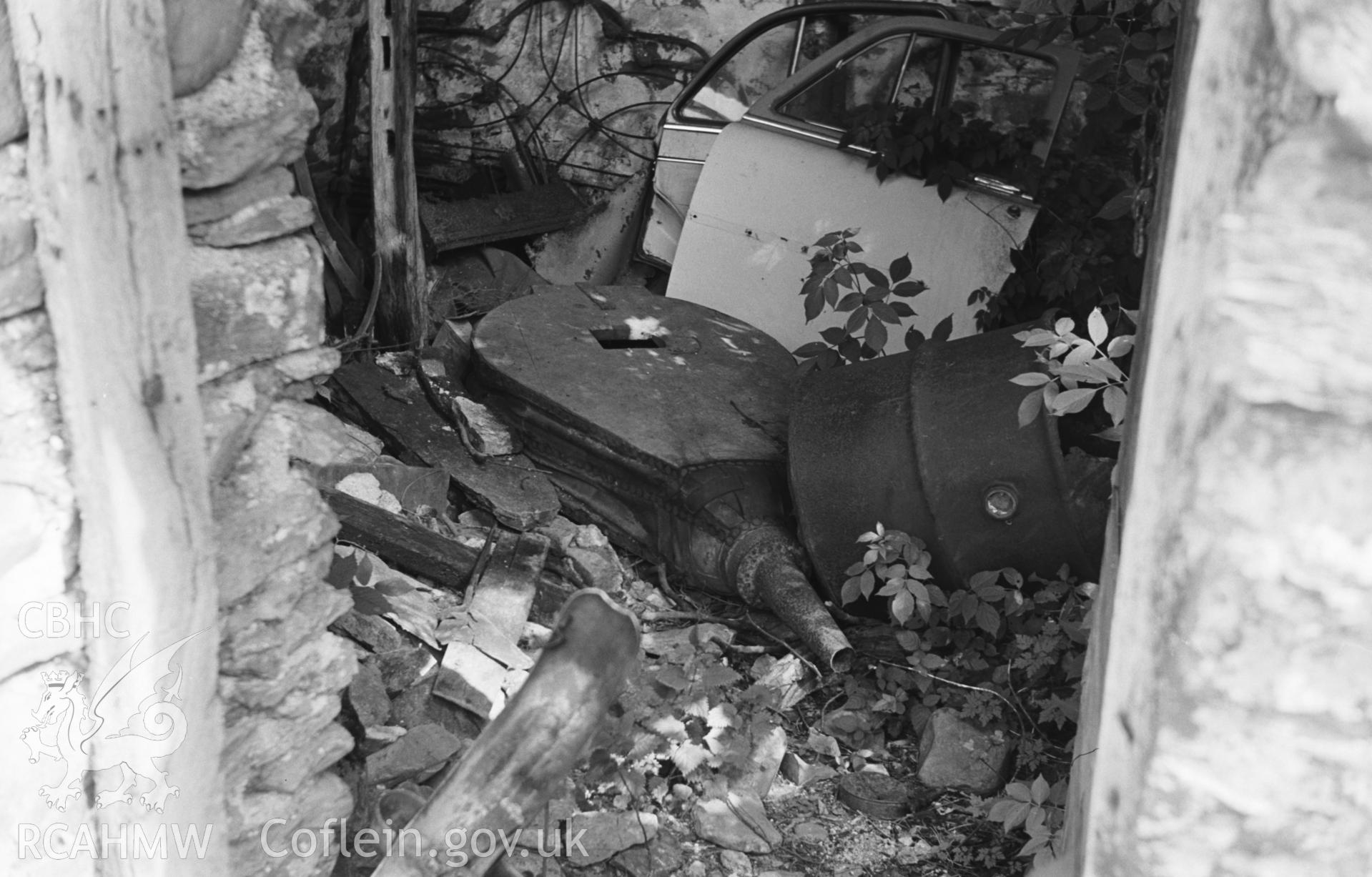 Digital copy of a black and white negative showing large bellows in ruined smithy just south of Clettwr and east of the road in Tre'r-Ddol village. Car doors give scale. Photographed by Arthur O. Chater on 17th August 1967, from Grid Reference SN 660 922.