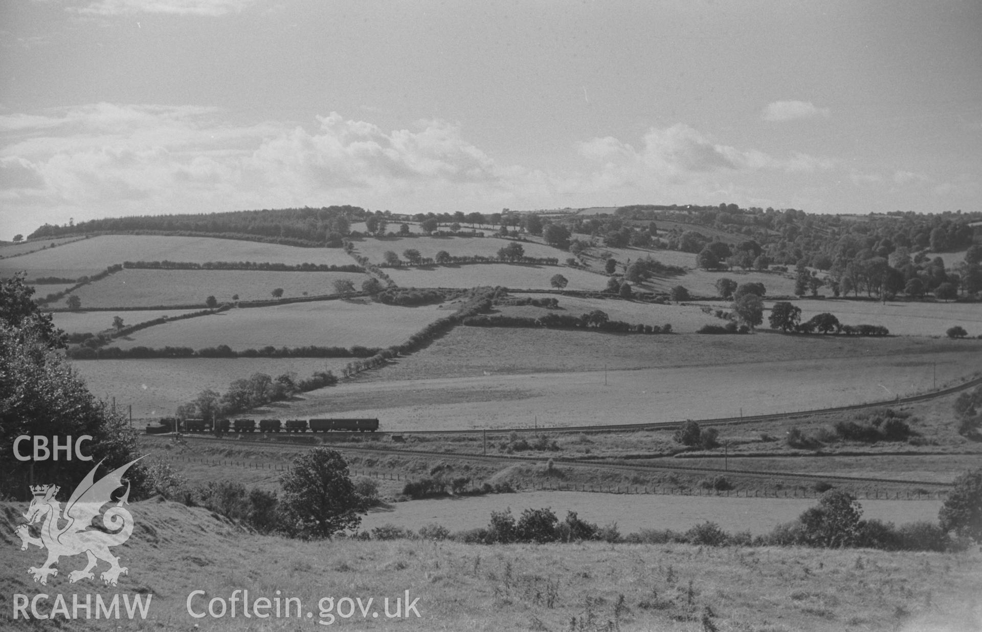 Digital copy of a black and white negative showing milk train at the junction of the Aberaeron line and the Lampeter-Aberystwyth line. Dyffryn Wood on skyline at left. Photographed by Arthur O. Chater on 4th September 1966 looking west from SN 591 505.