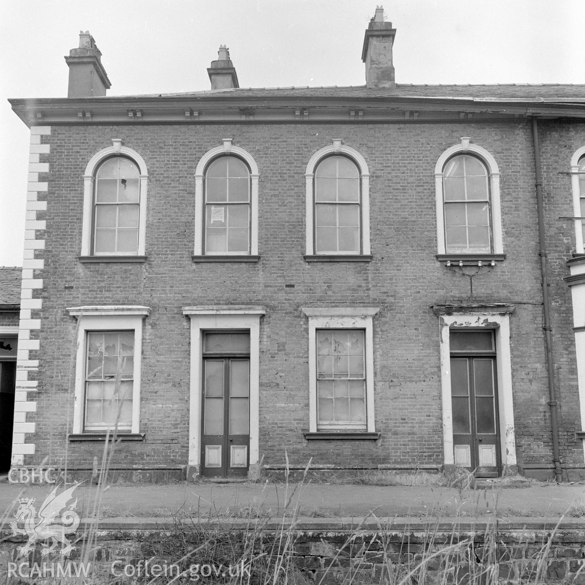 Digital copy of a black and white negative showing a view of the railtrack side elevation of Llanidloes Railway Station taken by D B Hague.