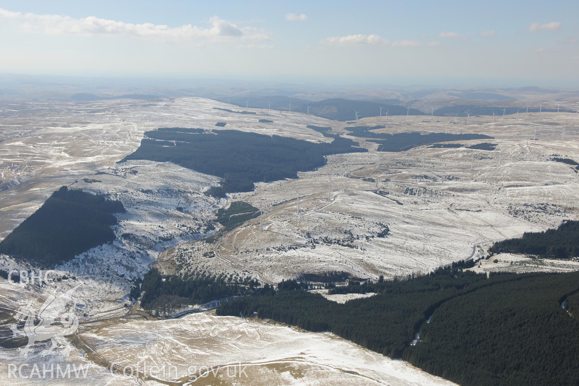 View from the east of Pen Lluest-y-Carn barrow, with Cefn Croes wind farm beyond. View looking north west towards Llangurig. Oblique aerial photograph taken during the Royal Commission's programme of archaeological aerial reconnaissance by Toby Driver on 2nd April 2013.