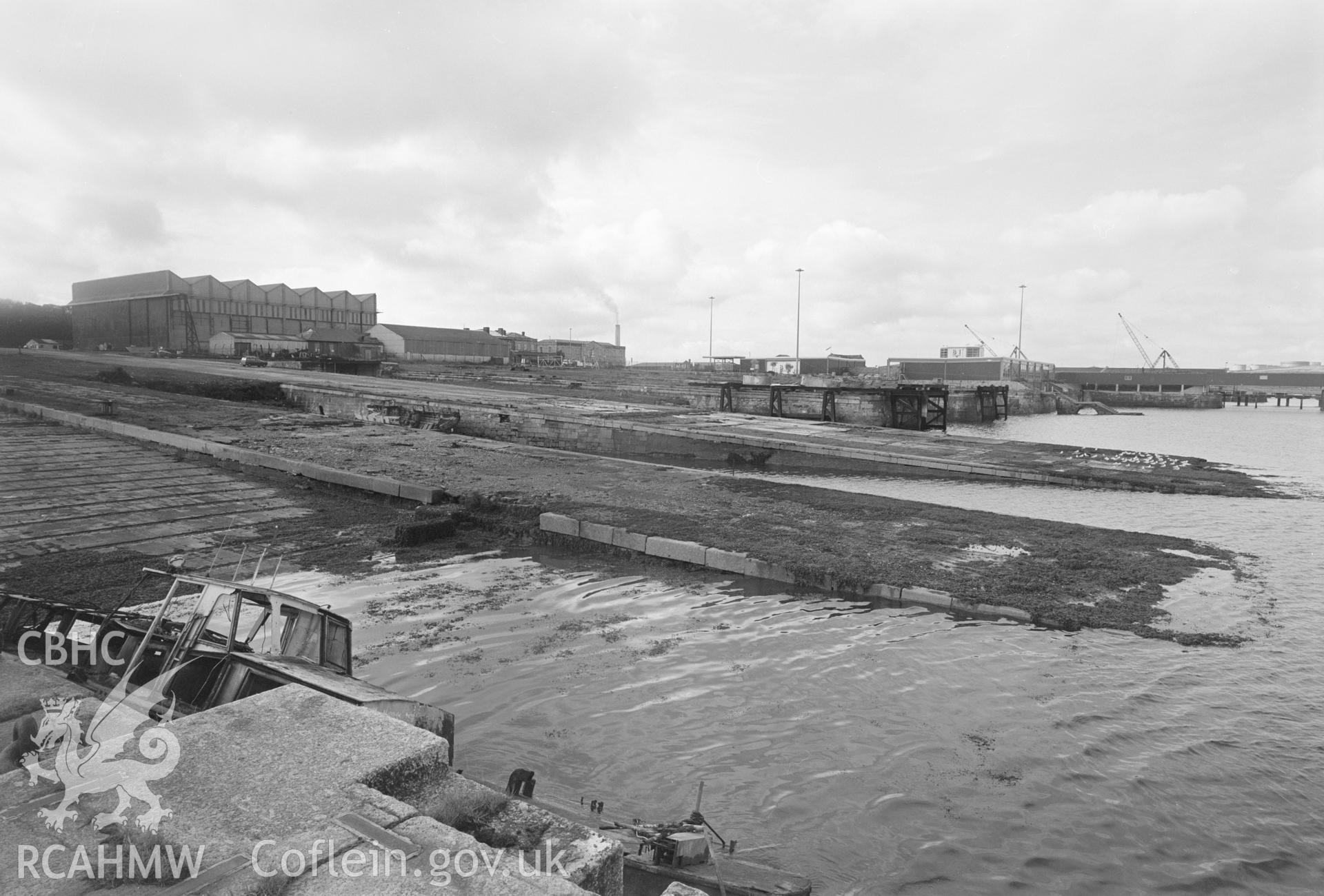 Digital copy of a black and white negative showing Old Royal Dockyard Pembroke - seaward N end of building slips 12 (front) & 11 with intermediate piers lowered to accommodate seaplane wings looking SW. taken by RCAHMW.