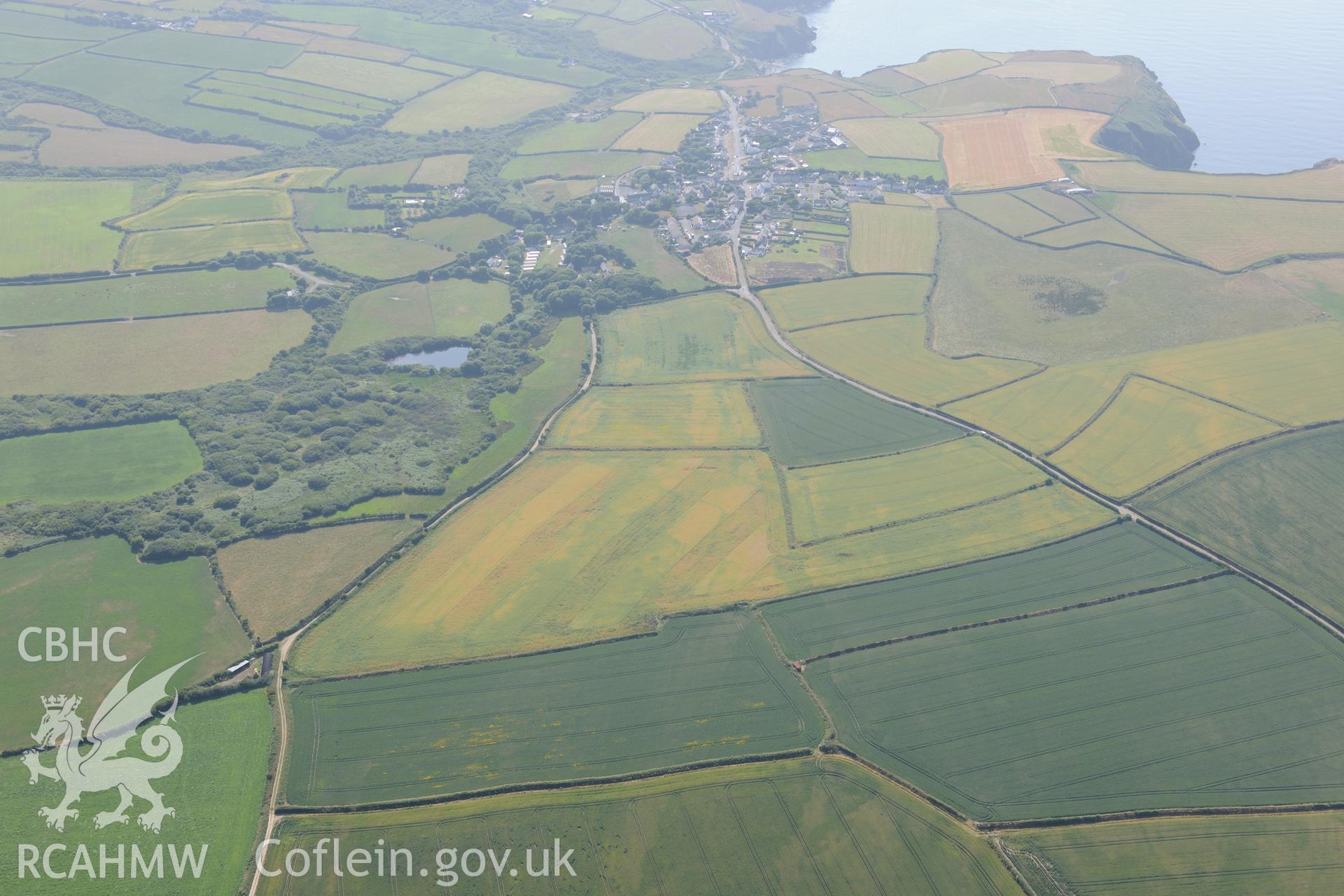 Mynydd Hwnt or Commins Mawr defended enclosure and the village of Trefin, Pembrokeshire. Oblique aerial photograph taken during the Royal Commission?s programme of archaeological aerial reconnaissance by Toby Driver on 16th July 2013.