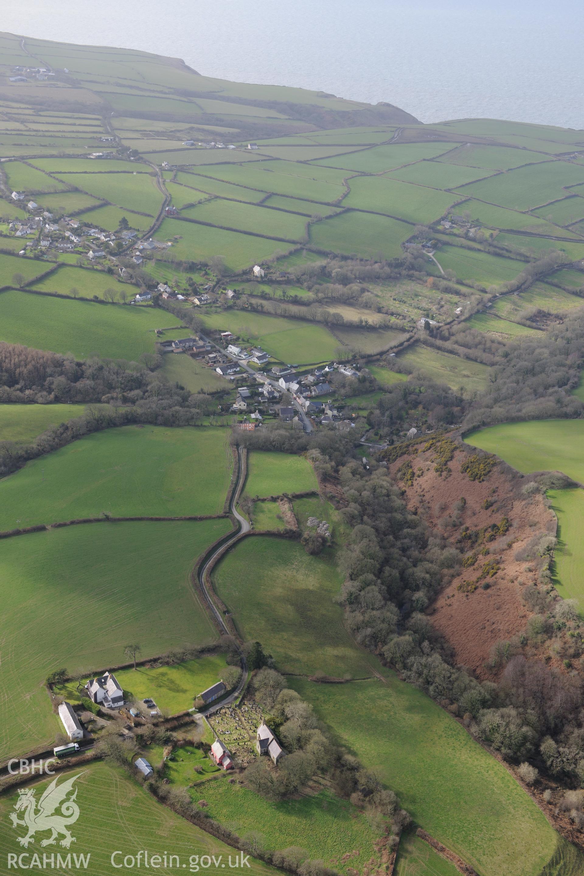 St. Mynno, St. David and St. Andrew's church, Glandwr Isaf Camp and the village of Moylgrove. Oblique aerial photograph taken during the Royal Commission's programme of archaeological aerial reconnaissance by Toby Driver on 13th March 2015.