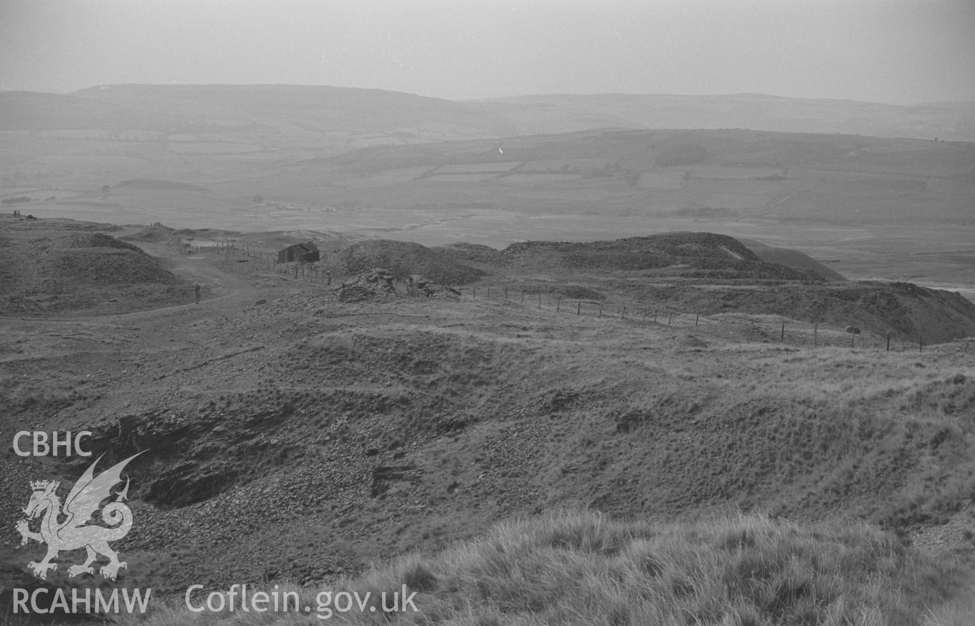 Digital copy of black & white negative showing view across old opencast workings of the late 18th century to main Esgair Mwyn Mine beyond; Glog-Fawr mine in distance on right. Photographed by Arthur O. Chater on 28th August 1966 from Grid Ref SN 756 691.