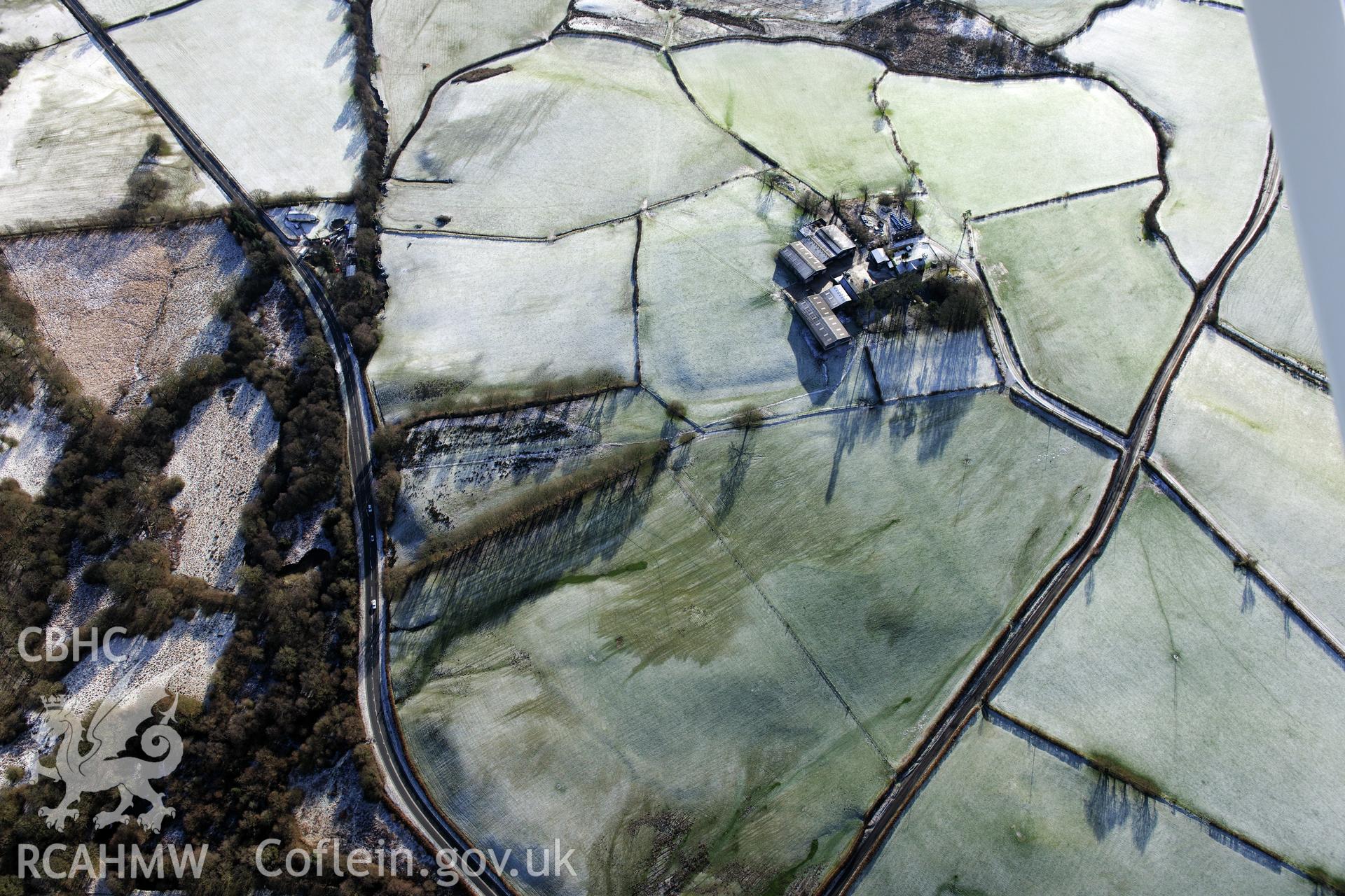 Twdin or Caerau Motte, Caerau Roman fort and military settlement, and the Roman road from Carmarthen to Castell Collen (RR623). Oblique aerial photograph taken during the RCAHMW?s programme of archaeological aerial reconnaissance by Toby Driver 15/01/2013.