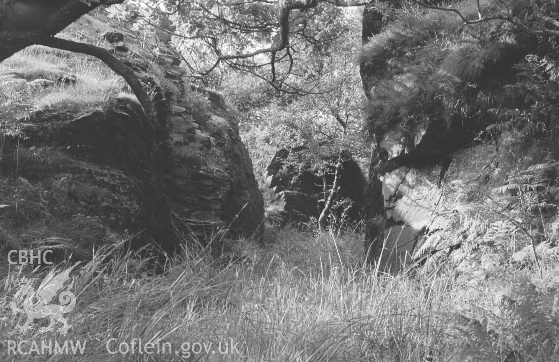 Digital copy of black & white negative showing view north west through cutting in rock where mine tramway runs round side of ridge just north west of lowest reservoir at Bryndyfi Lead Mine. Photograph by Arthur O. Chater, August 1966. Grid Ref SN 683 935.