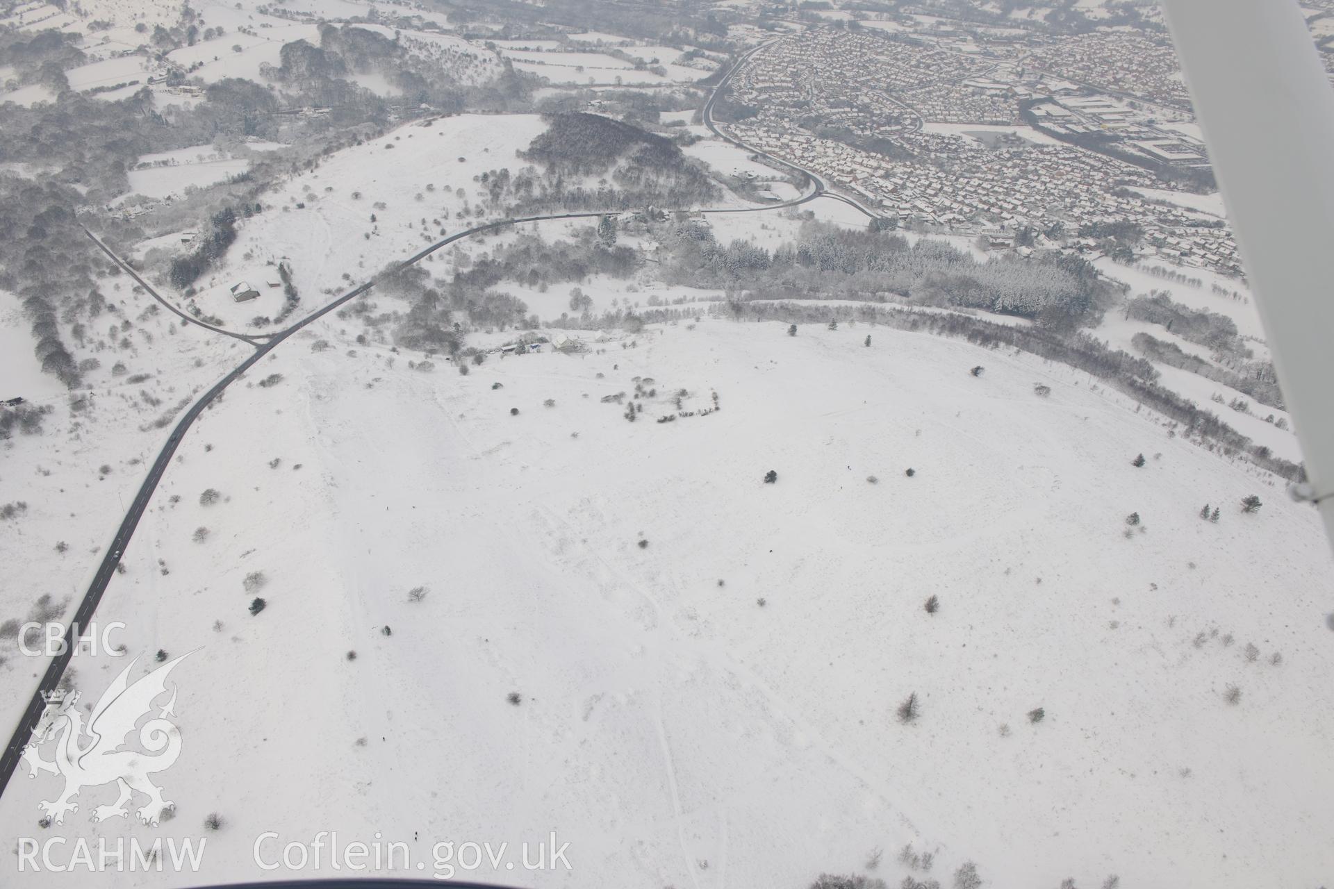 Caerphilly Common with Caerphilly covered reservoir (below rectangular cluster of trees). The town of Caerphilly lies beyond. Oblique aerial photograph taken during the Royal Commission?s programme of archaeological aerial reconnaissance by Toby Driver on 24th January 2013.