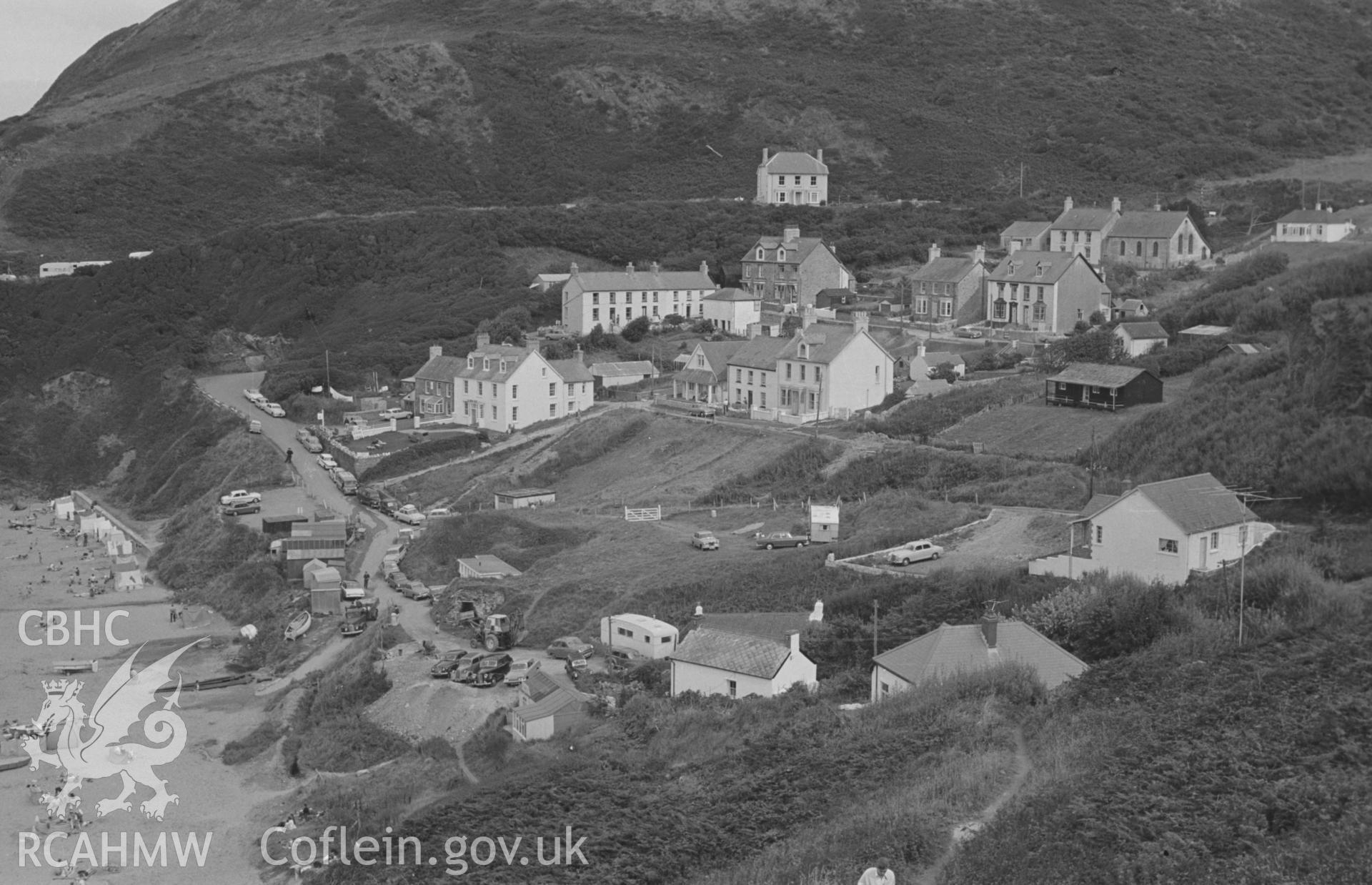 Digital copy of a black and white negative showing Tresaith, beach, cars and holidaymakers, Cardigan. Photographed in August 1963 by Arthur O. Chater from the footpath along the cliffs at SN 2761 5148, looking east.