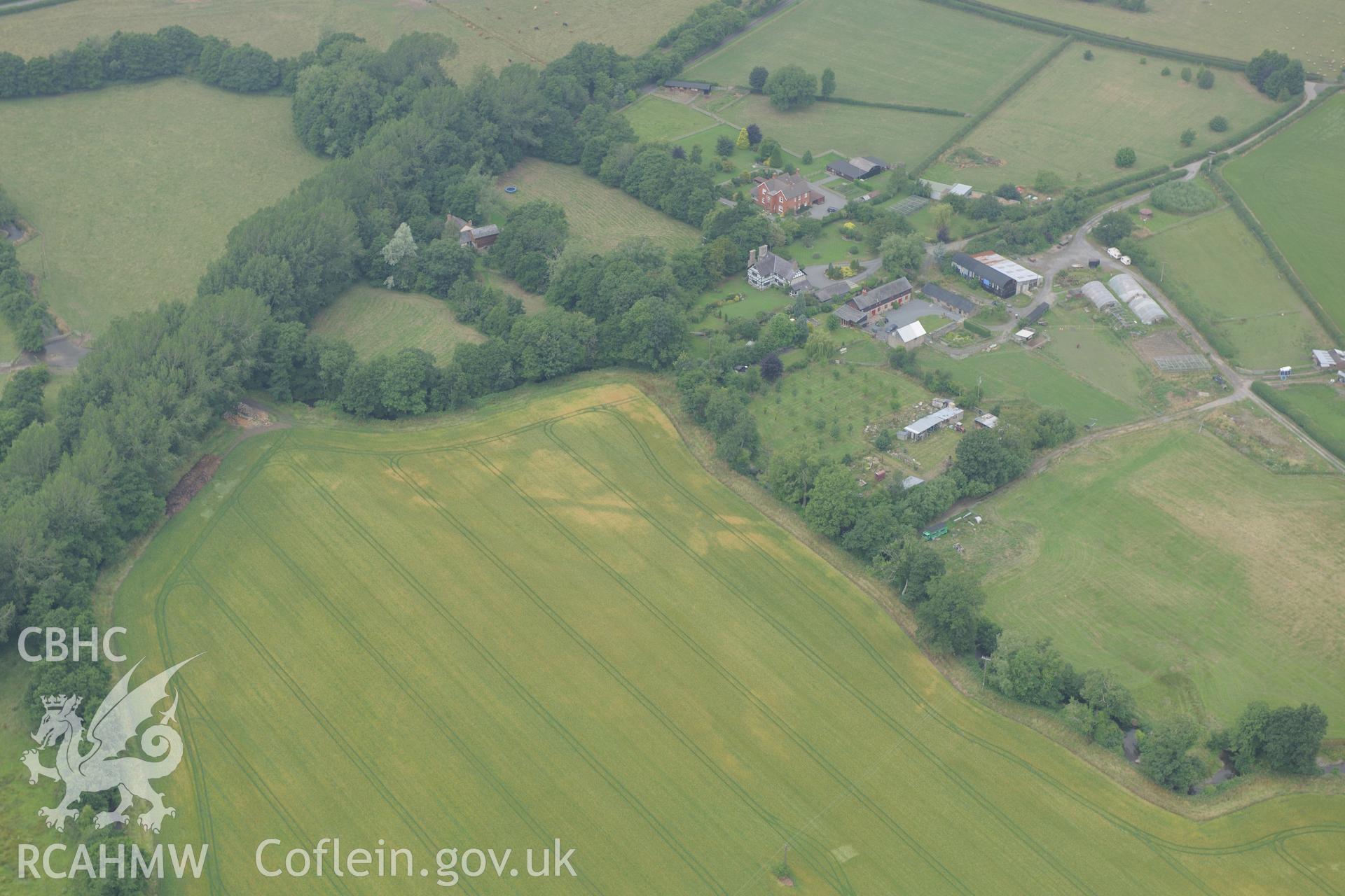 Wegnall farmhouse with the Wegnall cropmarks in the field below, on the Wales-England border south east of Presteigne. Oblique aerial photograph taken during the Royal Commission?s programme of archaeological aerial reconnaissance by Toby Driver on 1st August 2013.