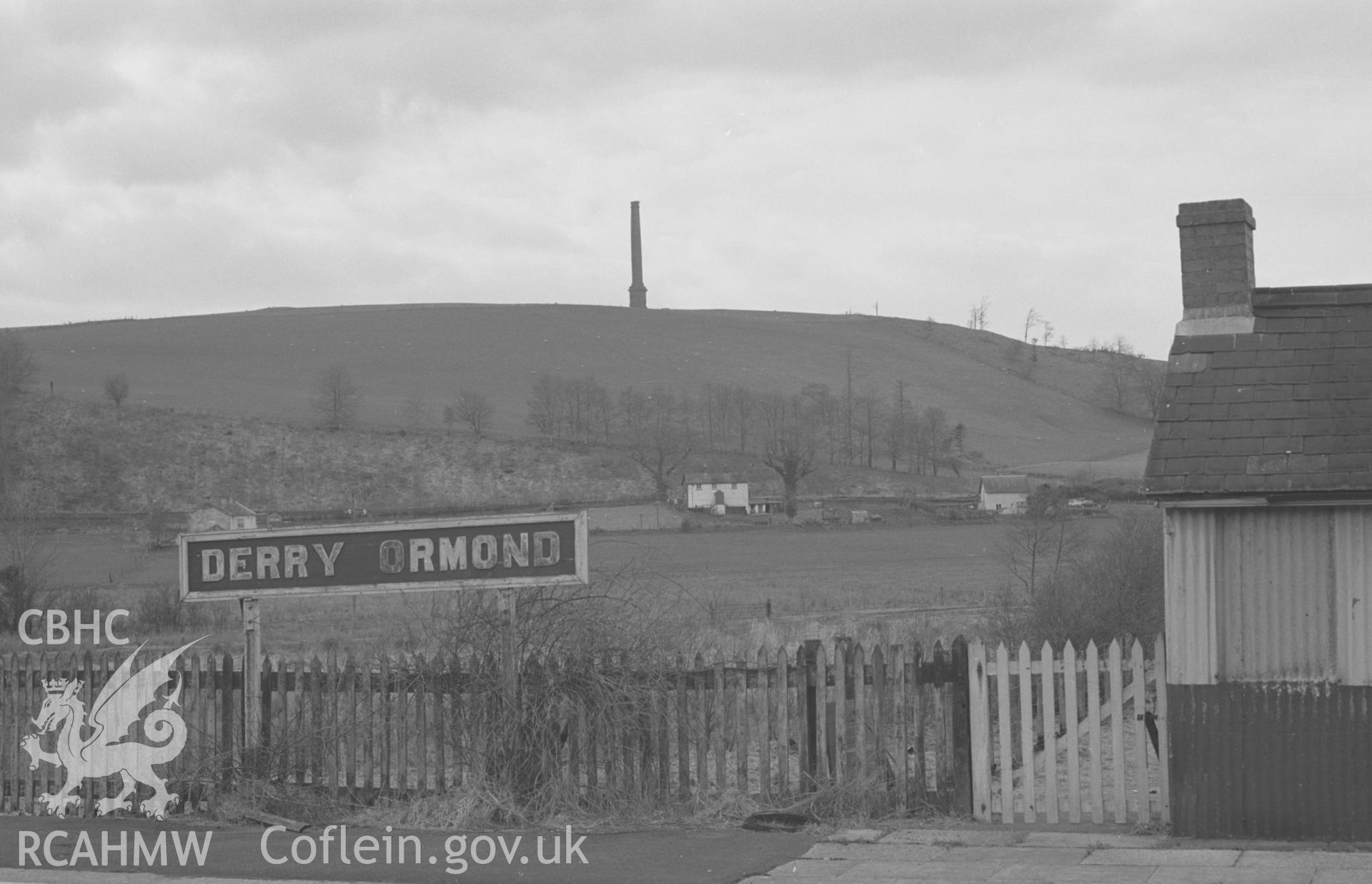 Digital copy of black & white negative showing view of (disused) Derry Ormond station, with Derry-Ormond tower and remains of Bettws Plantations on hillside beyond. Photographed by Arthur O. Chater on 7th April 1968 looking west north west from SN 597 514.