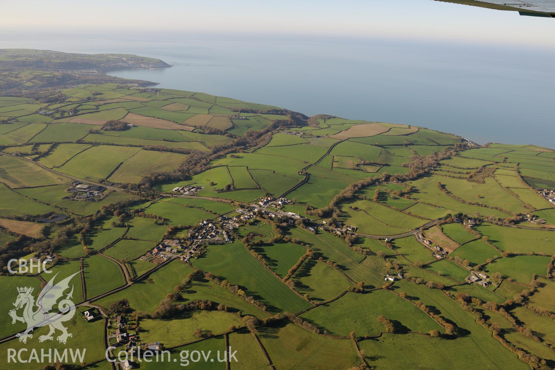 View from the south east of Llwyncelyn, near Aberaeron, with Cardigan Bay beyond. Oblique aerial photograph taken during the Royal Commission's programme of archaeological aerial reconnaissance by Toby Driver on 2nd November 2015.