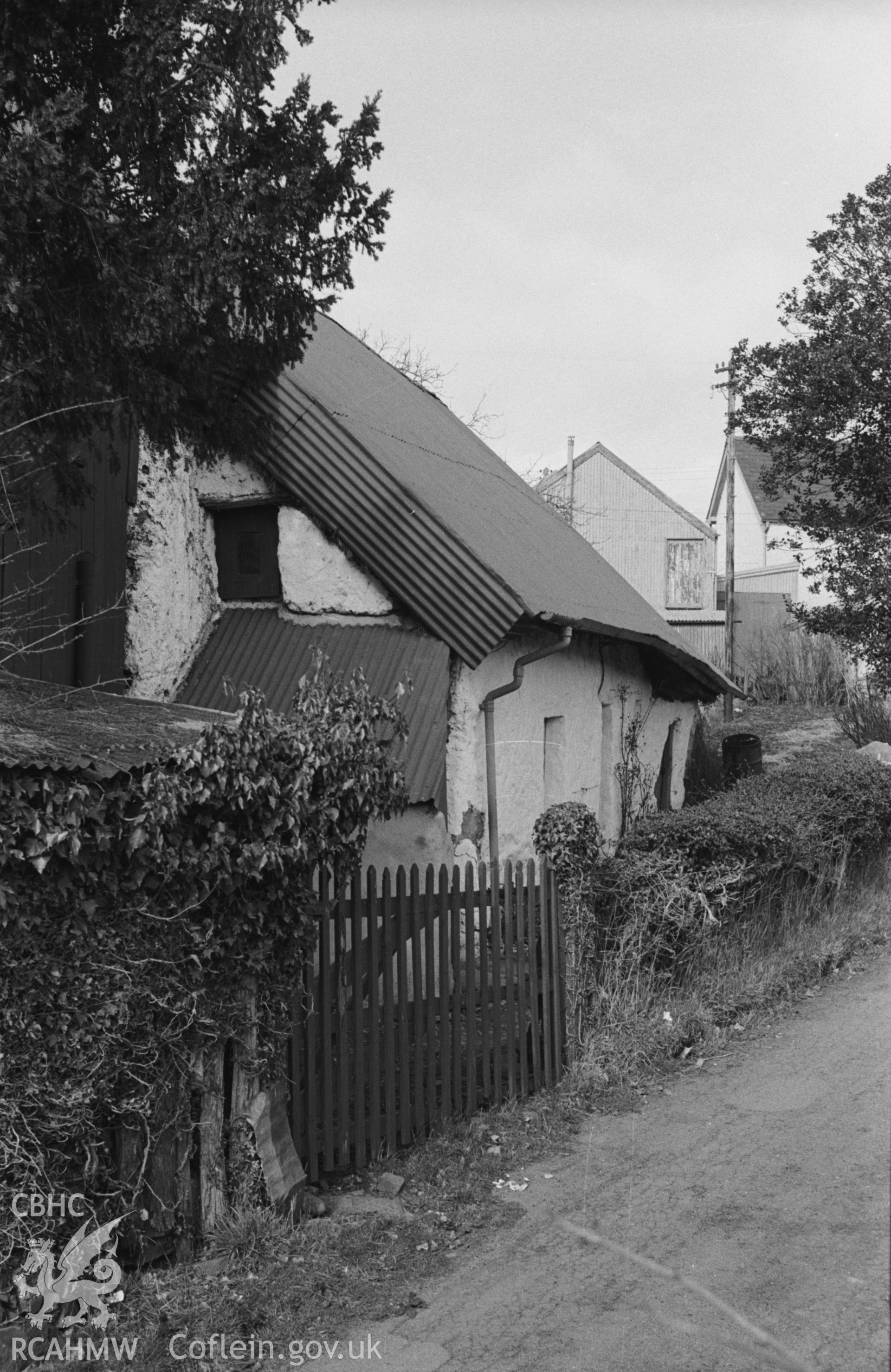 Black and White photograph showing very large mud and thatch cottage in street to the south east of the mmain square at Llangeitho. Photographed by Arthur Chater in April 1963 from Grid Reference SN 6195 5967, looking north.