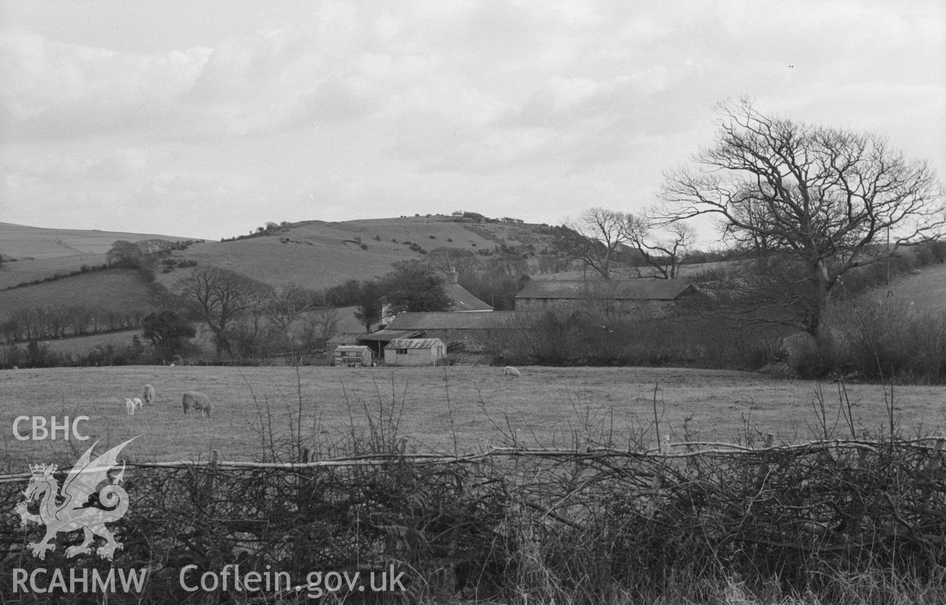 Black and White photograph showing view of Allt-Goch Farm with Caer Allt-Goch beyond, from the Staylittle-Dolybont road, Talybont. Photographed by Arthur Chater in April 1963 from Grid Reference SN 639 889, looking south south east.