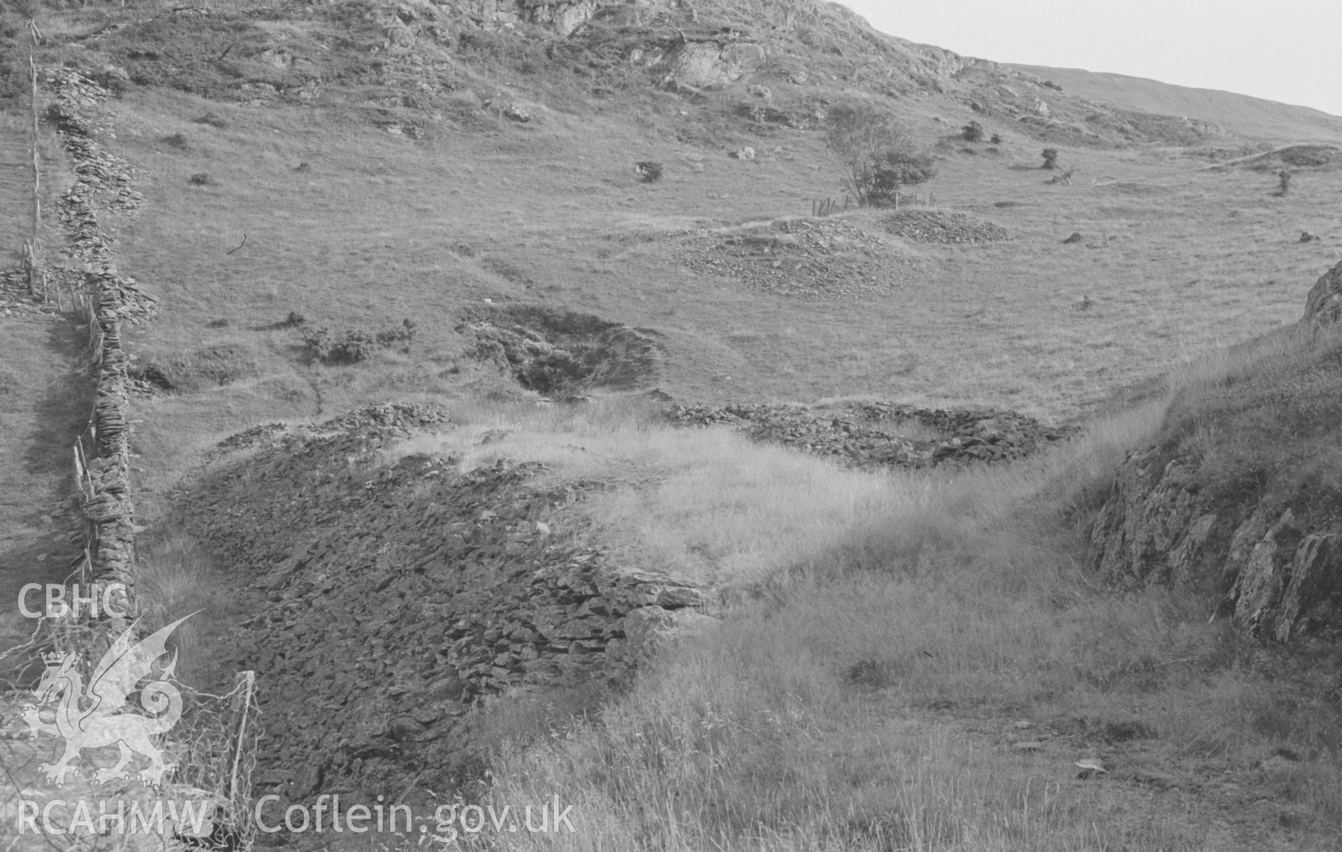 Digital copy of black & white negative showing view looking along stone embankment of mine tramway to terminus at Bryndyfi mine, shafts on the hillside to the right. Photographed by Arthur O. Chater in August 1966 looking south from Grid Ref SN 687 939.