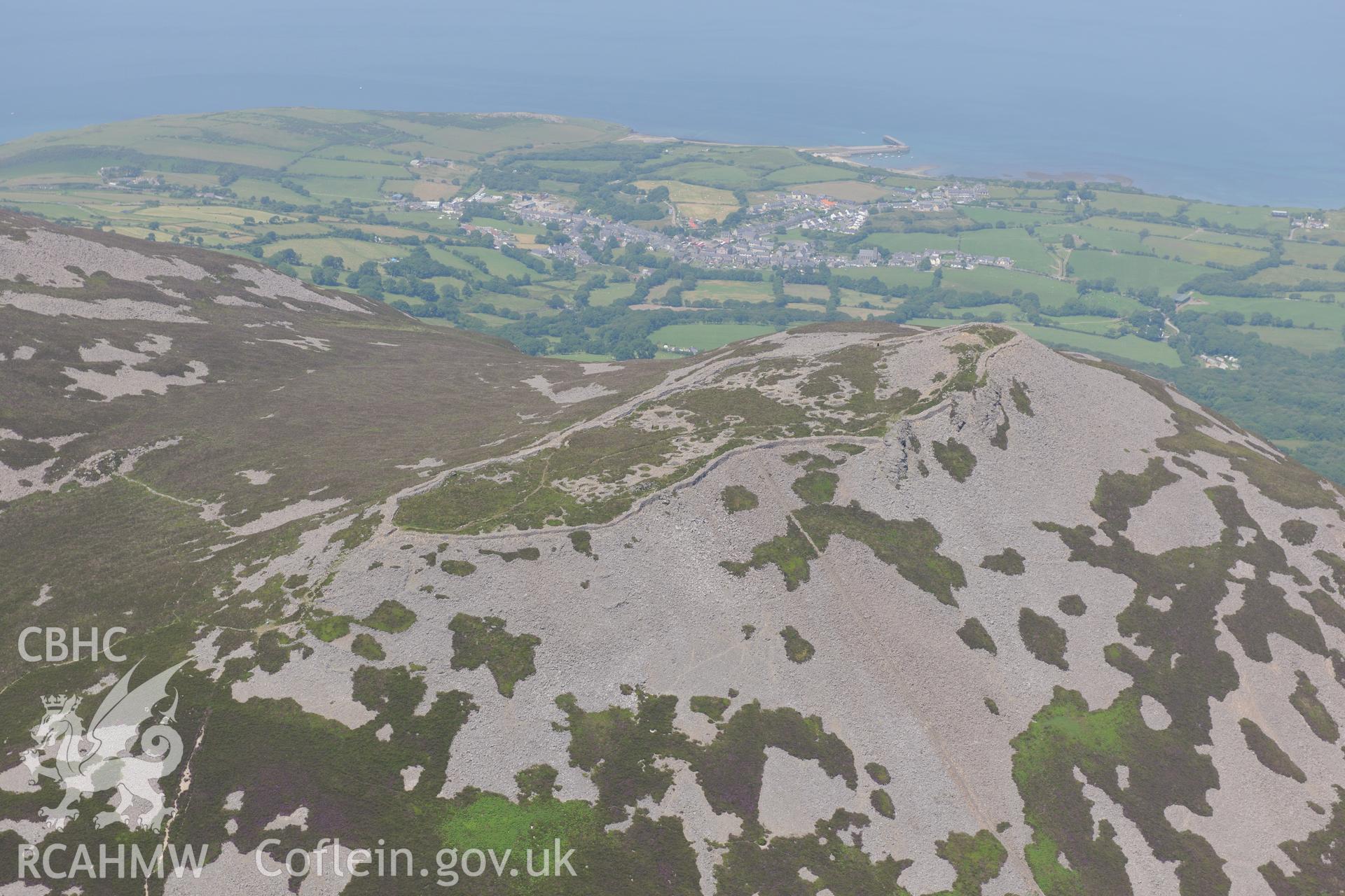 Tre'r Ceiri hillfort with the village of Trefor beyond, on the Lleyn Peninsula. Oblique aerial photograph taken during the Royal Commission?s programme of archaeological aerial reconnaissance by Toby Driver on 12th July 2013.