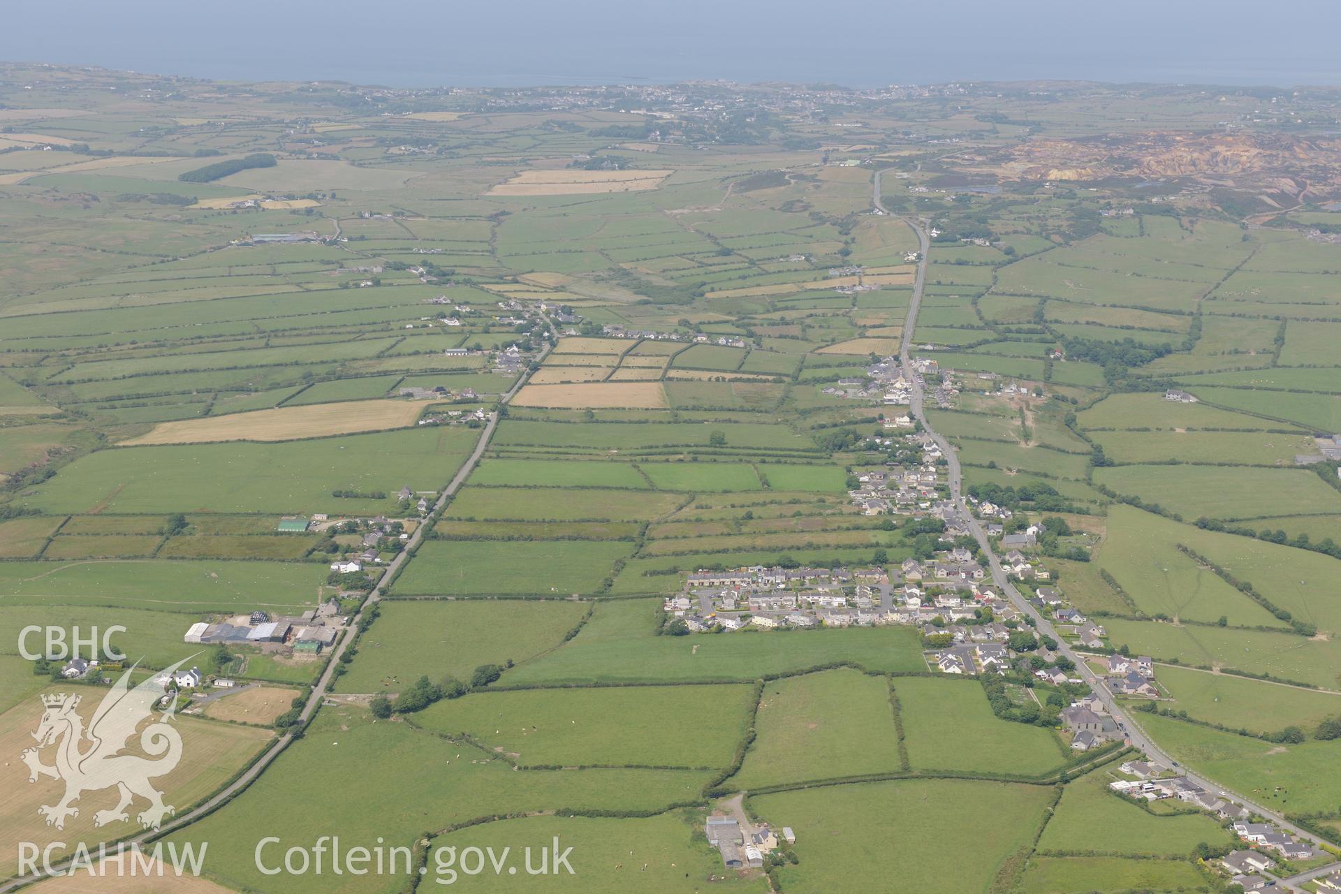 The village of Rhosybol, with the Parys Mountain Copper Mines and Amlwch beyond, north Anglesey. Oblique aerial photograph taken during the Royal Commission?s programme of archaeological aerial reconnaissance by Toby Driver on 12th July 2013.