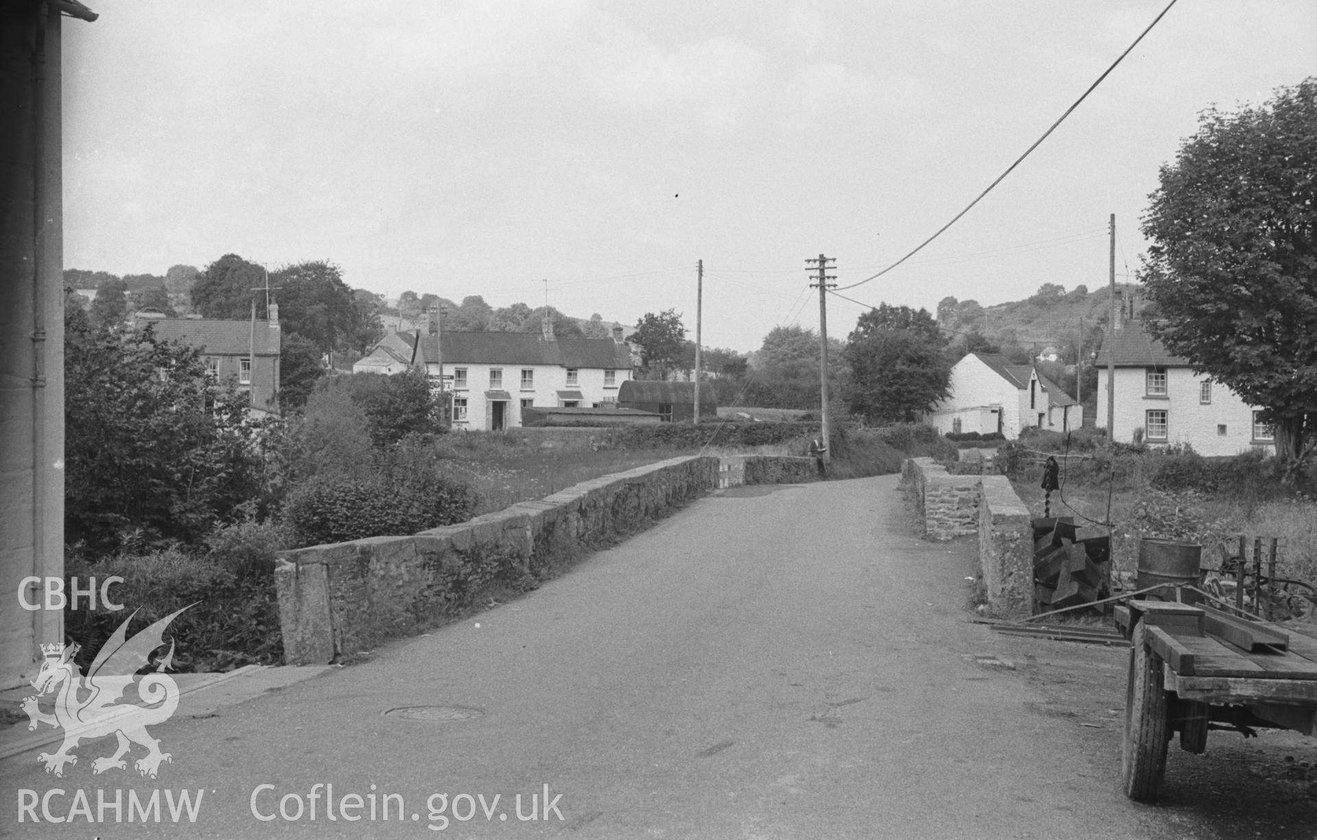 Digital copy of black & white negative showing view across the bridge over the Clettwr Fawr towards Post Office at Talgarreg. Photographed by Arthur O. Chater in August 1965 looking north west from Grid Reference SN 4256 5116. Bridge destroyed c. 1977.