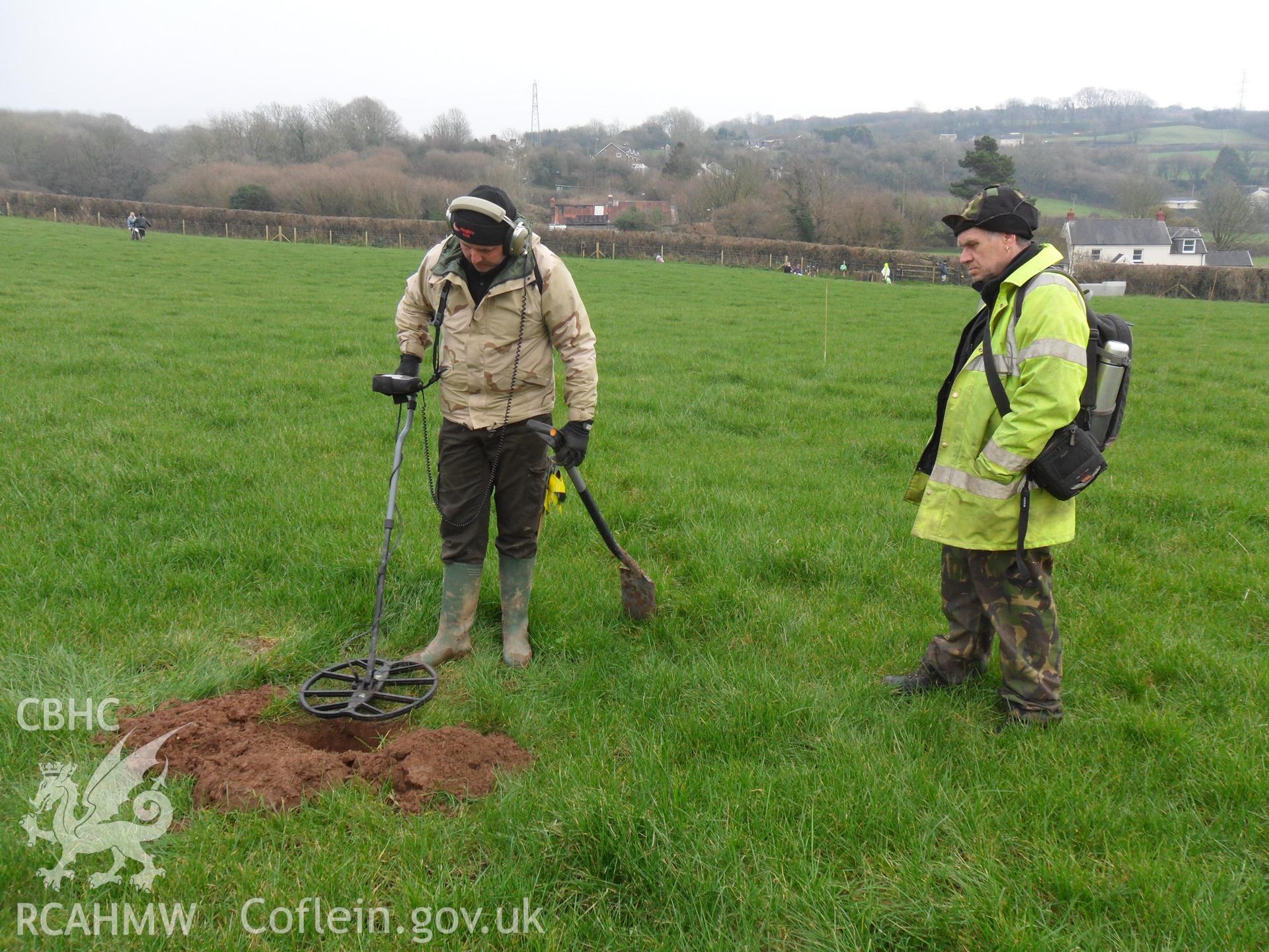 Digital colour photograph of metal detecting at Maes Gwenllian battlefield. From report no. 1050 - Maes Gwenllian battlefield, part of the Welsh Battlefield Metal Detector Survey, carried out by Archaeology Wales.