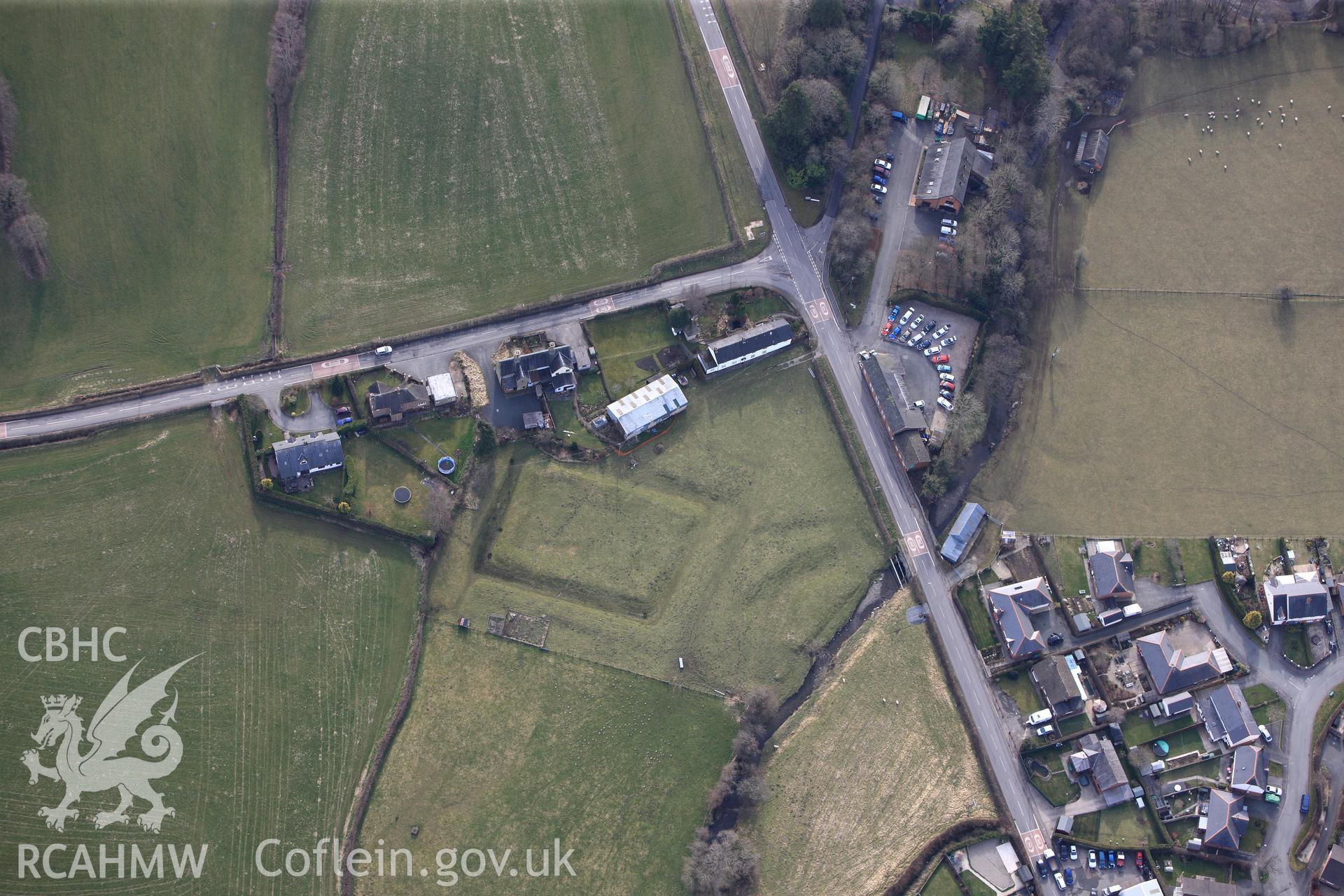 Tregynon moat, with Concrete Cottage and the Tithe Barn cottages above, north west of Newtown. Oblique aerial photograph taken during the Royal Commission?s programme of archaeological aerial reconnaissance by Toby Driver on 28th February 2013.