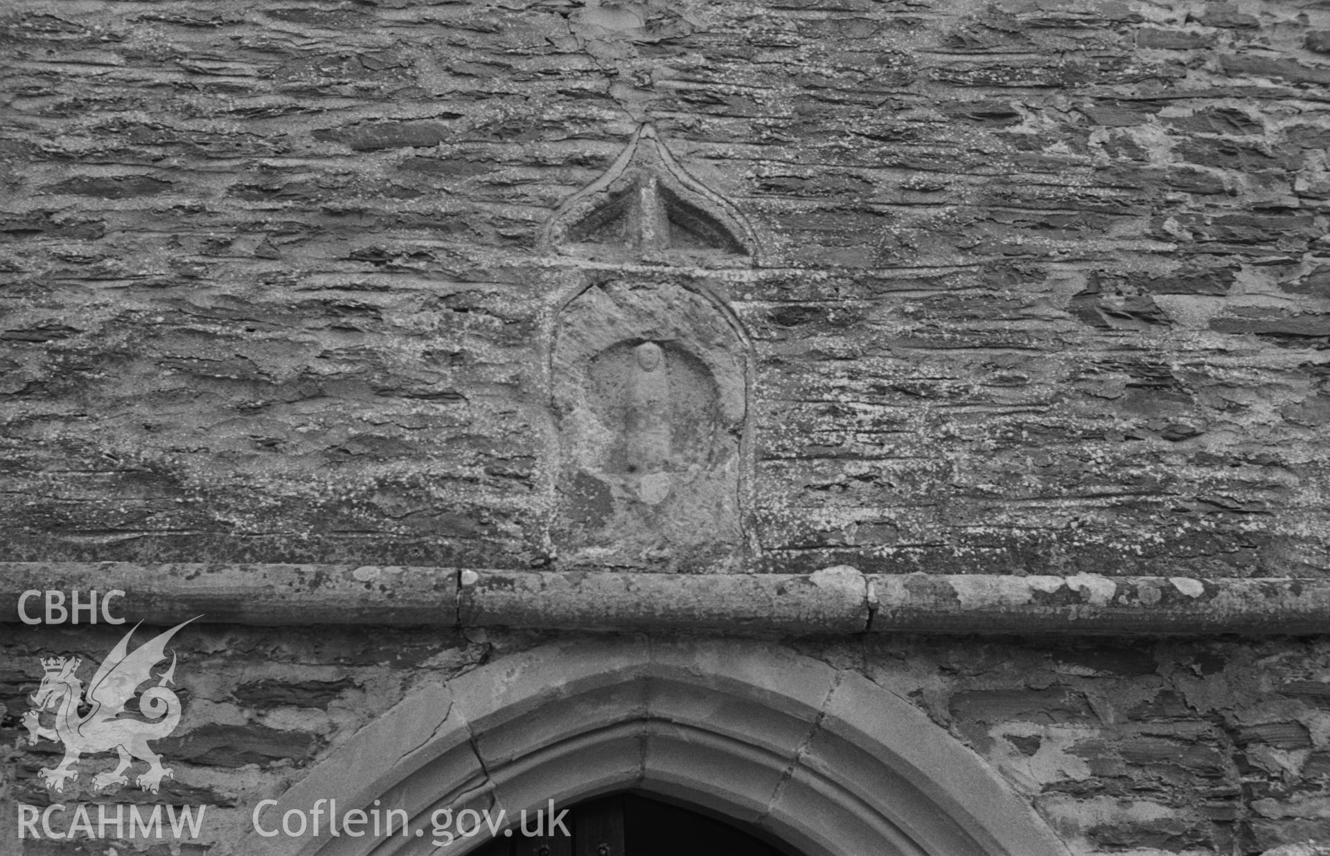 Digital copy of a black and white negative showing relief sculpture above the west door of St Gwynin's church, Llanwnnen. Photographed in April 1963 by Arthur O. Chater from Grid Reference SN 5331 4727, looking east.