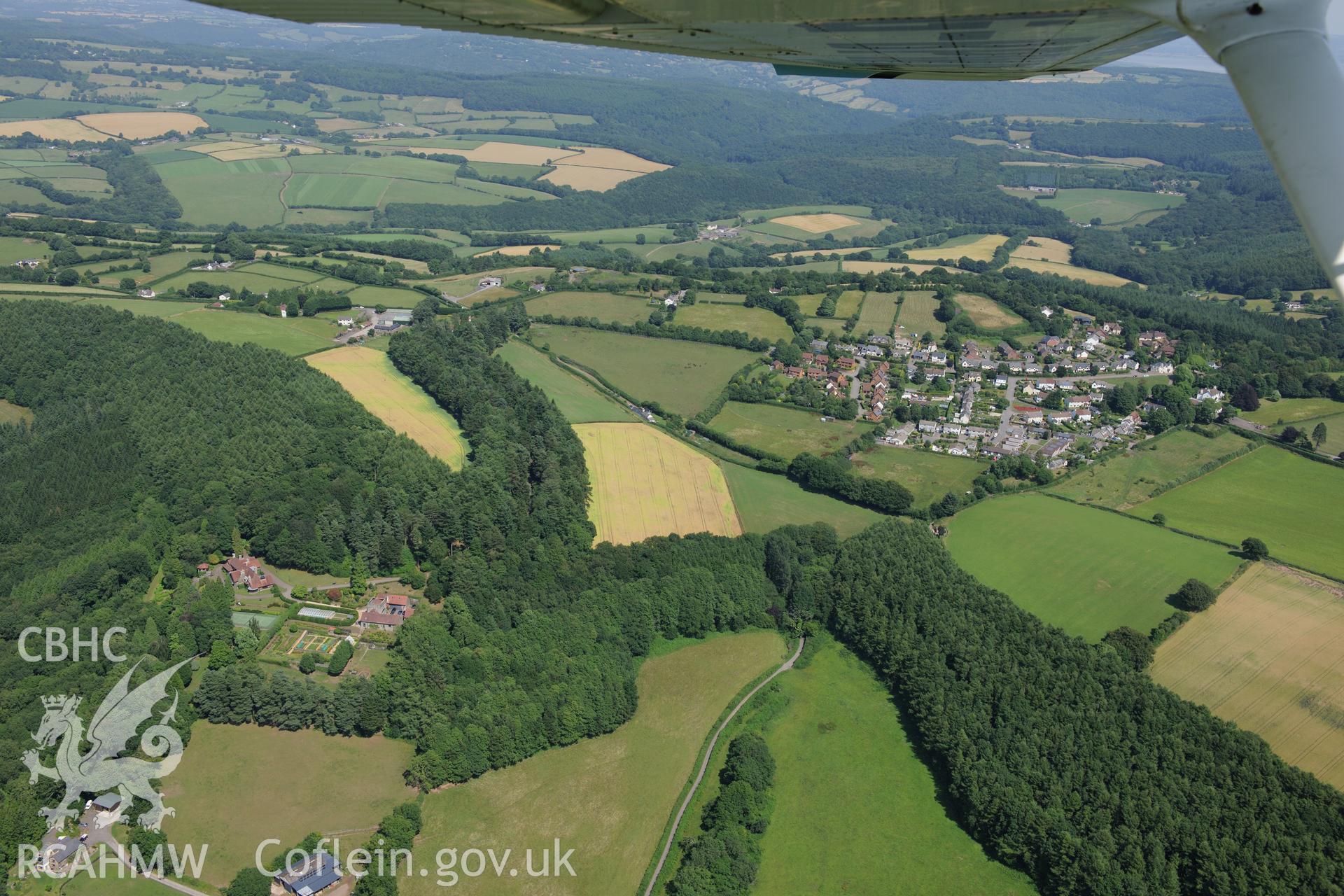 Tredean house and the village of Devauden, Monmouthshire, separated by Tredean wood. Oblique aerial photograph taken during the Royal Commission?s programme of archaeological aerial reconnaissance by Toby Driver on 1st August 2013.