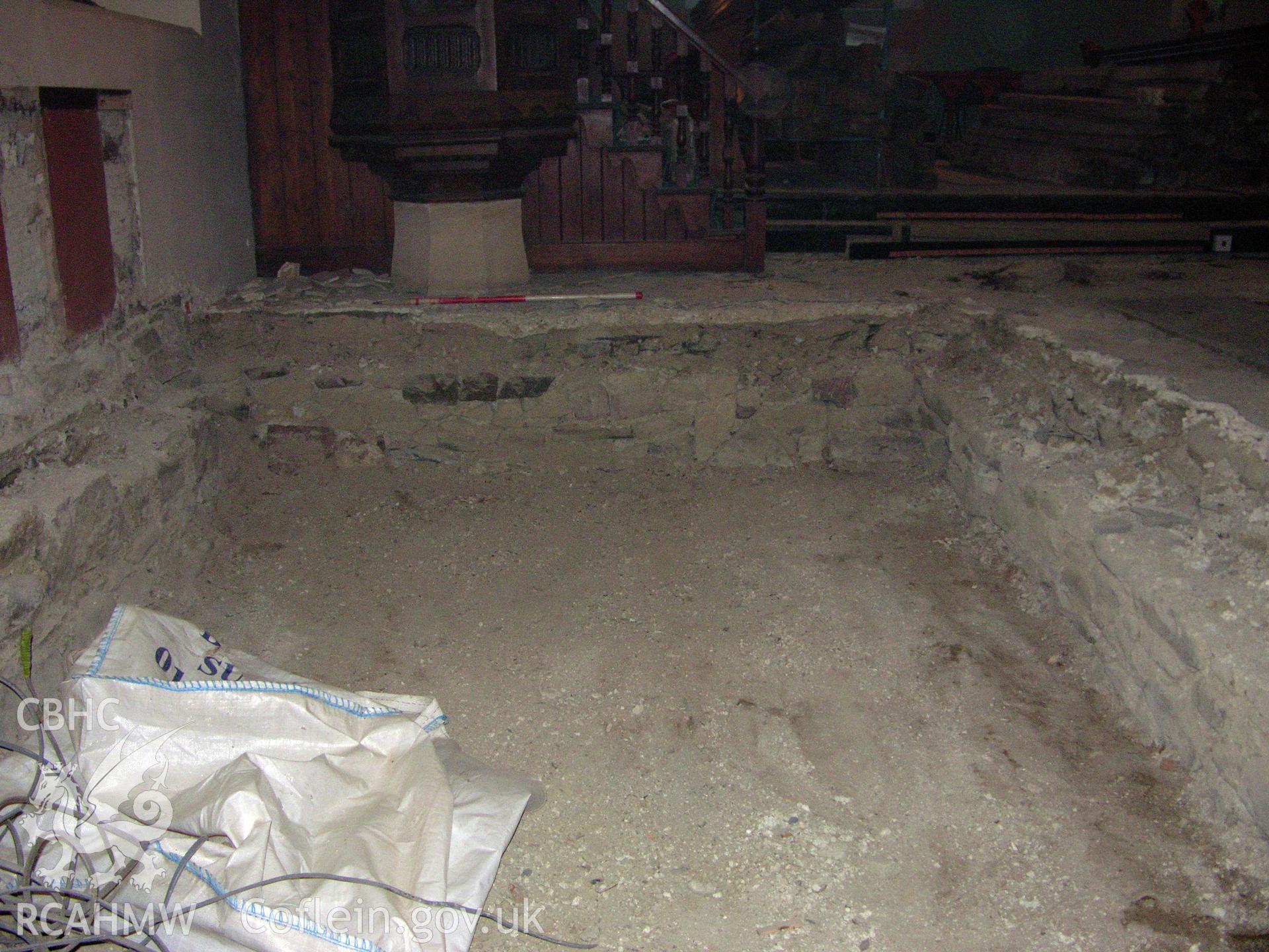 Digital colour photograph showing view of exposed foundation masonry below pulpit, scale 1x1m - part of an archaeological watching brief for St Michaels Church, Trefeglwys, Powys (CAP Report 602) by Chris E. Smith.