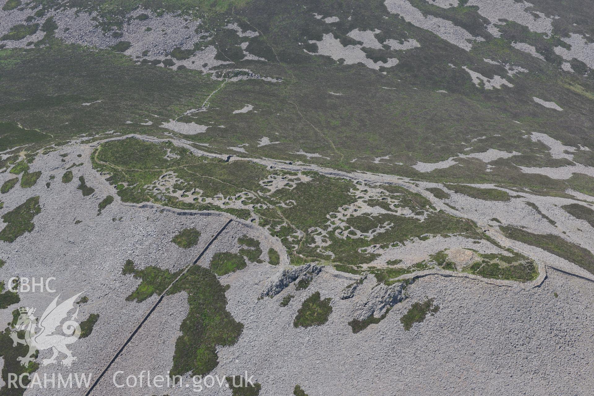 Tre'r Ceiri hillfort with the village of Trefor beyond, on the Lleyn Peninsula. Oblique aerial photograph taken during the Royal Commission?s programme of archaeological aerial reconnaissance by Toby Driver on 12th July 2013.