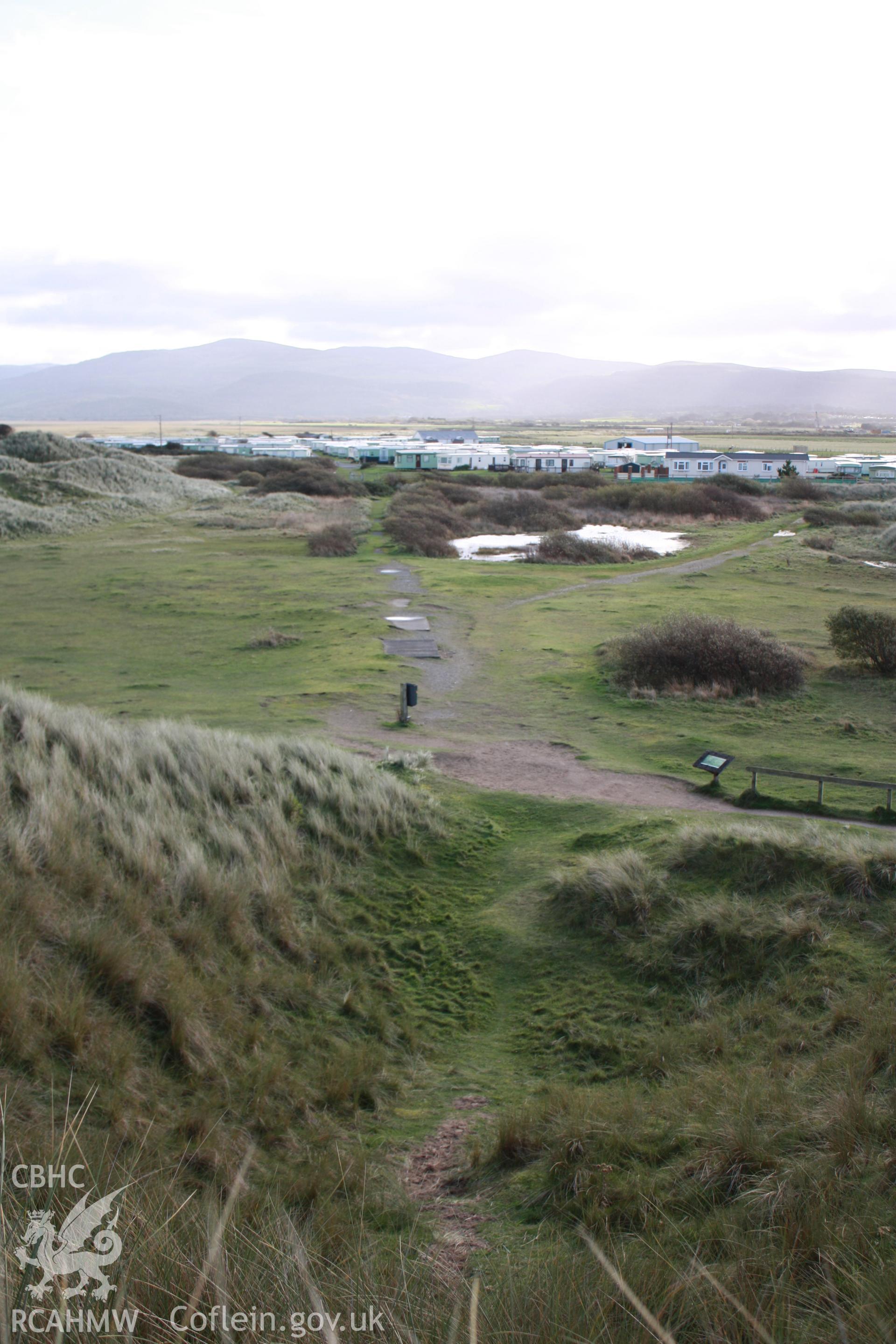View from rim of amphitheatre with remains of target post in immediate foreground down the slope, looking east along the length of the track.