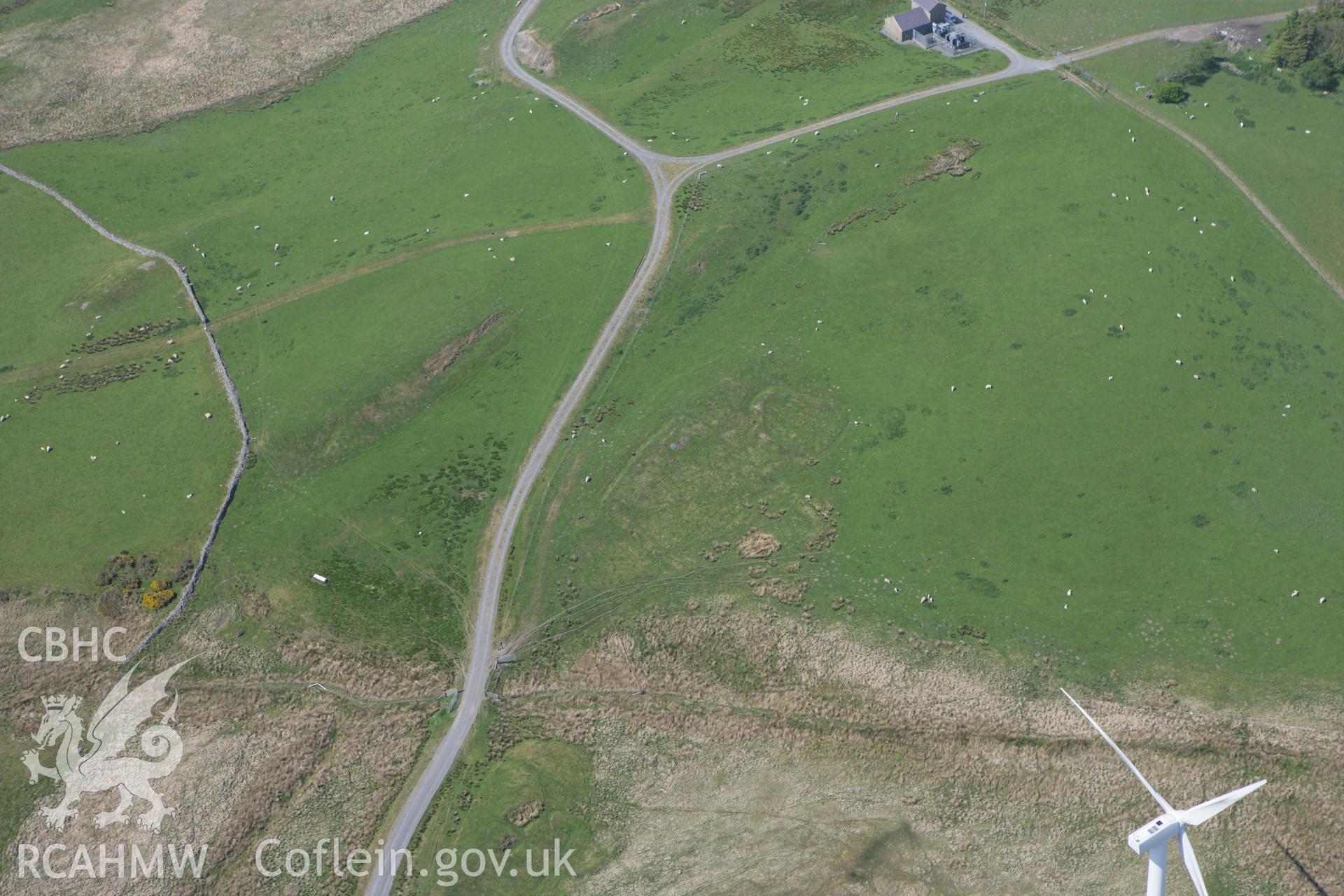 RCAHMW colour oblique photograph of Llangwyryfon windfarm, Banc Pwlldrainllwyn earthwork enclosure. Taken by Toby Driver on 25/05/2010.