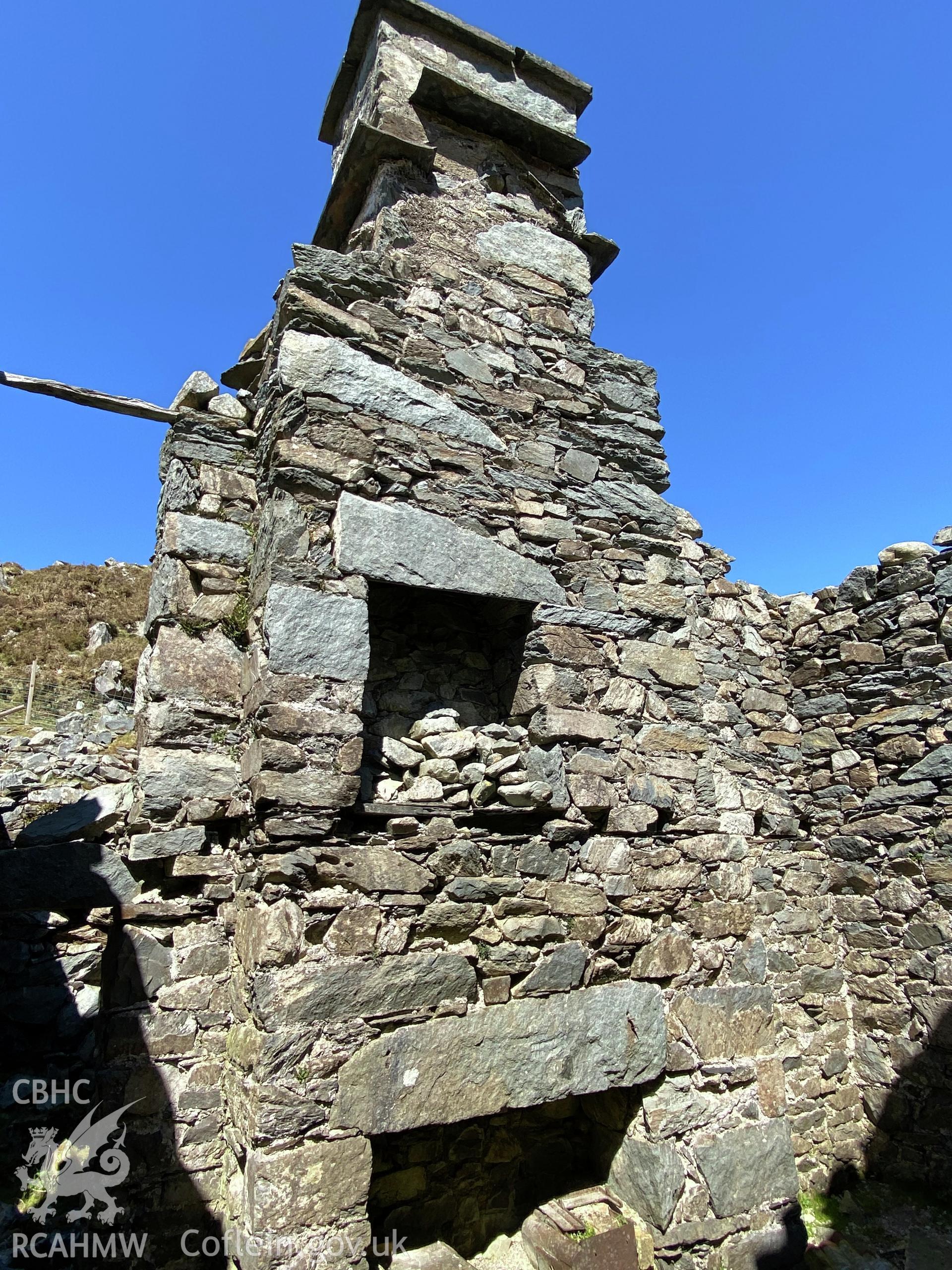 Digital colour photograph showing Hafotty-fach ruin (chimney stack and fire places in gable wall interior), produced by Paul R Davis in 2021.