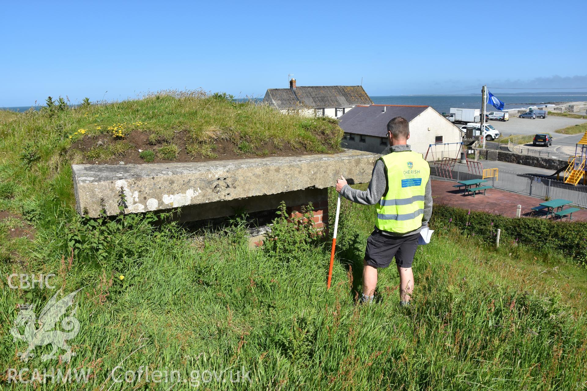 Seagull trench at Dinas Dinlle with figure and 1m scale. Photograph taken in June 2017 by Daniel Hunt as part of repeat monitoring and survey by the CHERISH project. © Crown: CHERISH PROJECT 2017. Produced with EU funds through the Ireland Wales Co-operation Programme 2014-2023. All material made freely available through the Open Government Licence.