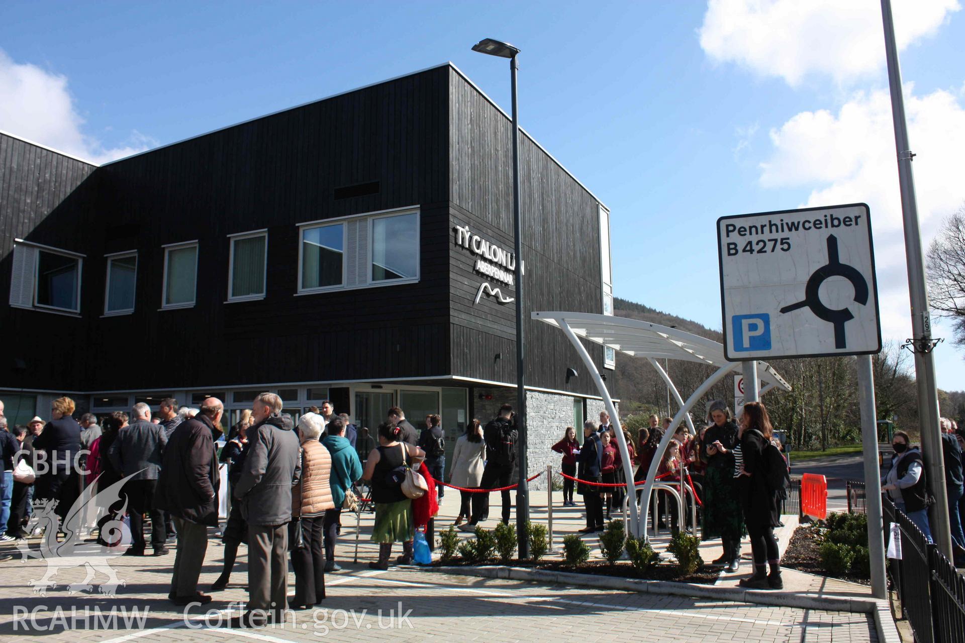 Digital colour photograph showing people at the unveiling of the statue of Elaine Morgan outside Tŷ Calon Lân, Oxford Street, Mountain Ash, taken 18 March, 2022.