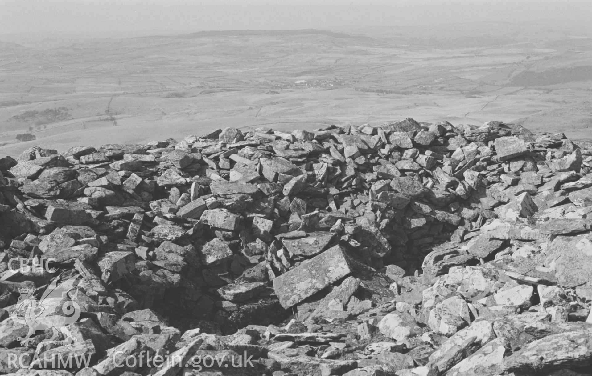 Digital copy of a black and white negative showing the hollow in the centre of the cairn of Carn Fflur, 1635ft. Pontrhydfendigaid in distance. Photographed by Arthur Chater on 12 April 1968. Looking north north west from Grid Reference SN 746 623.