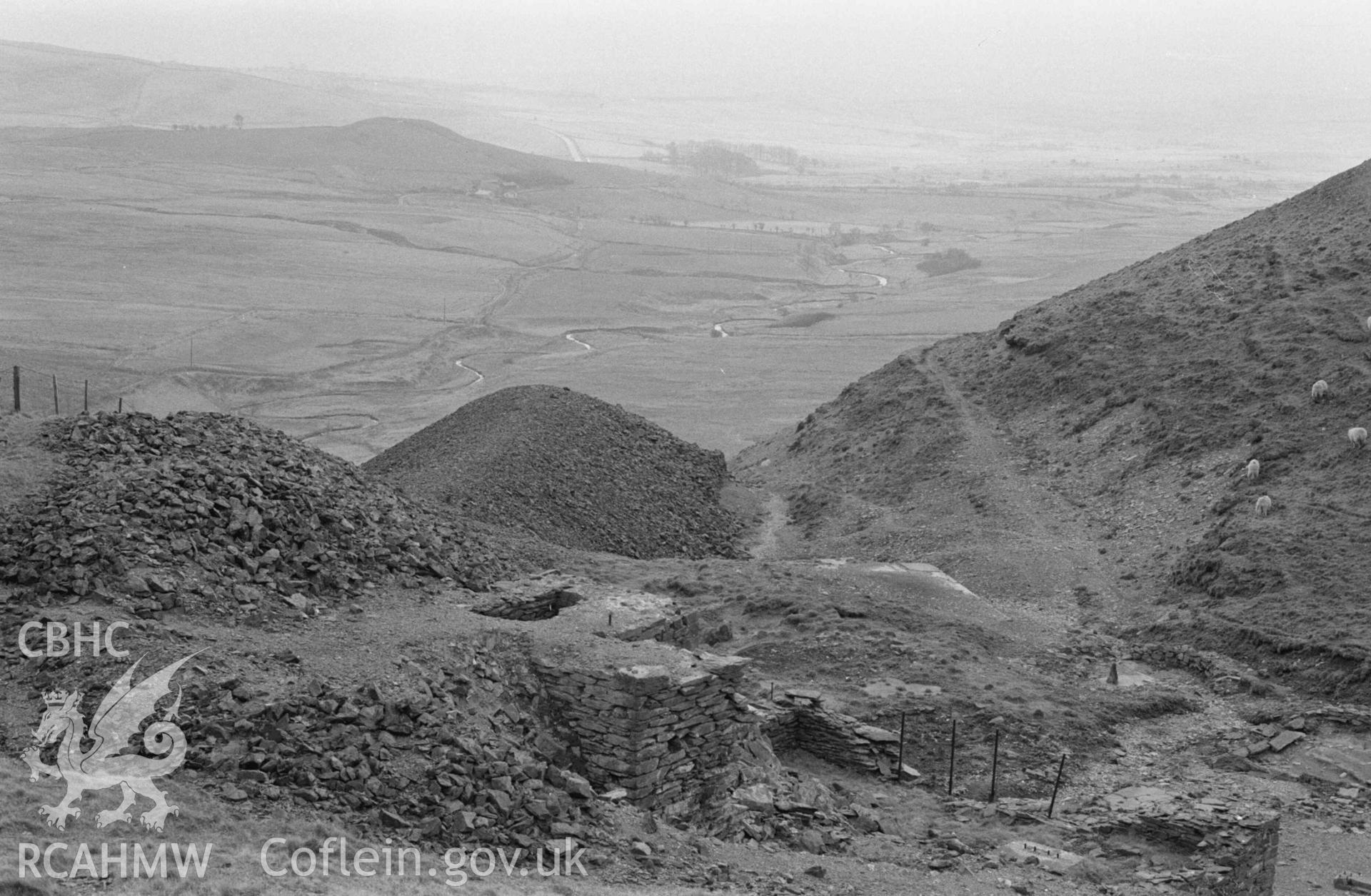 Digital copy of a black and white negative showing ruins and spoil heaps of Glog-Fawr leadmine, immediately south of reservoir; Marchnant stream in bottom of valley. Photographed by Arthur Chater on 14 April 1968. Looking south west from Grid Reference SN 749 707.