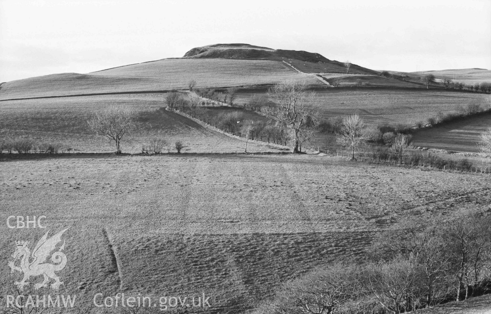 Digital copy of a black and white negative showing Castell Bwa Drain from Tan-yr-Ochr; old field system patterns showing up in low sun. Photographed by Arthur Chater on 5 January 1969. Looking west north west from Grid Reference SN 7172 7930.