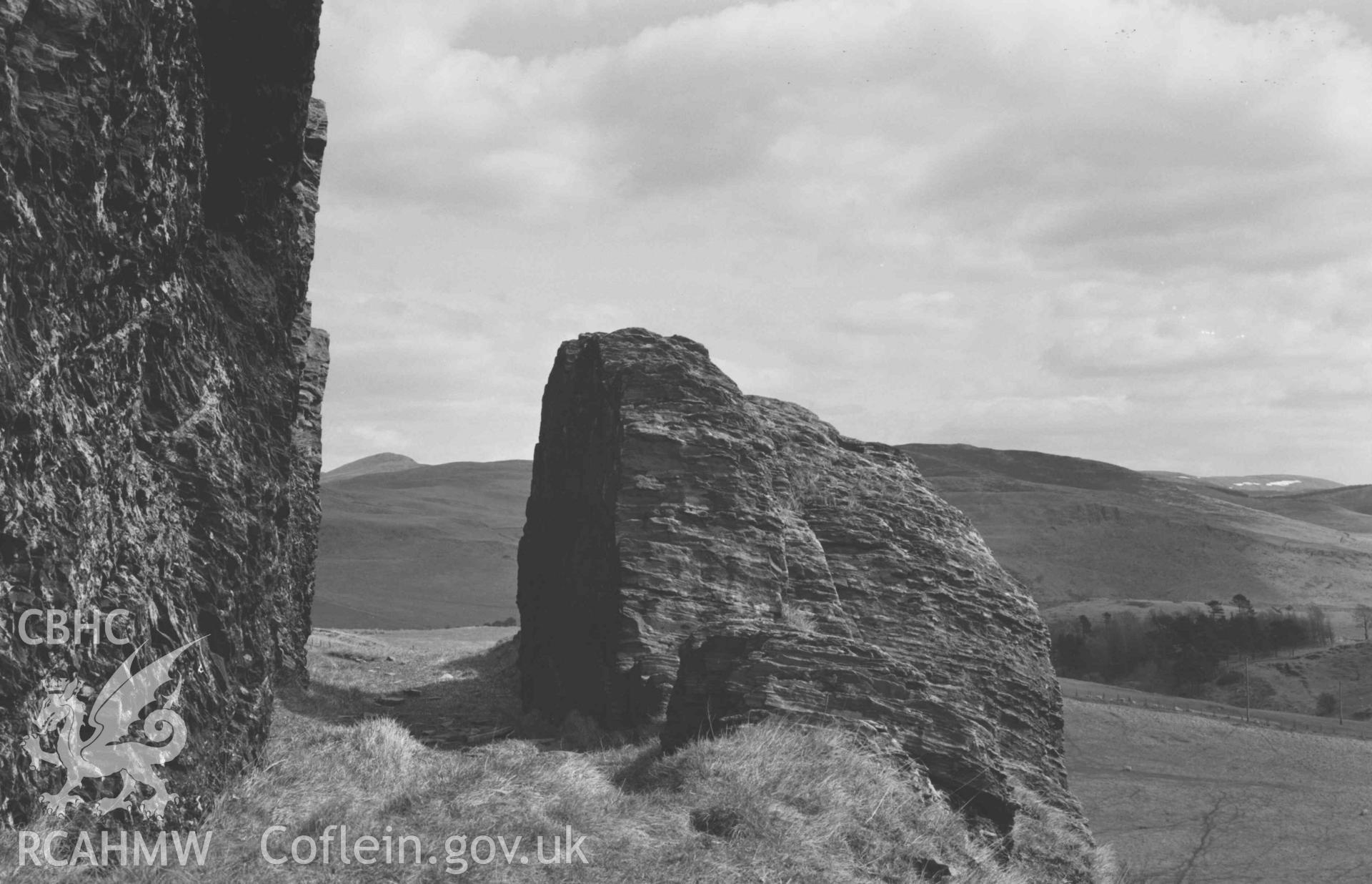 Digital copy of a black and white negative showing rock cutting of acqueduct on hillside 100m north of Ffynnon-Cadno. Photographed by Arthur Chater on 2 April 1969. Looking east from Grid Reference SN 7409 8071.