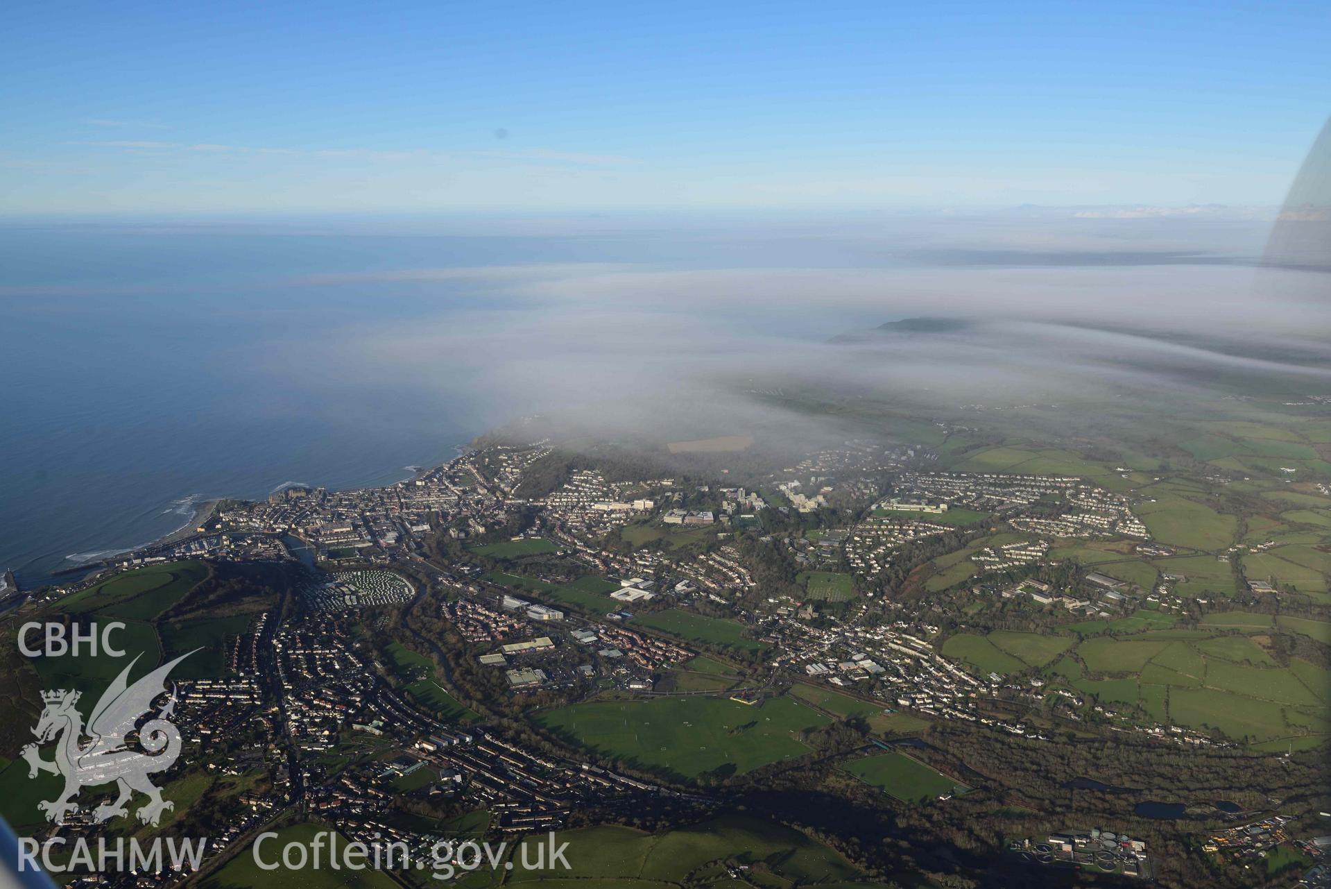 Oblique aerial photograph of Aberystwyth town under coastal fog, taken during the Royal Commission’s programme of archaeological aerial reconnaissance by Toby Driver on 12th January 2022