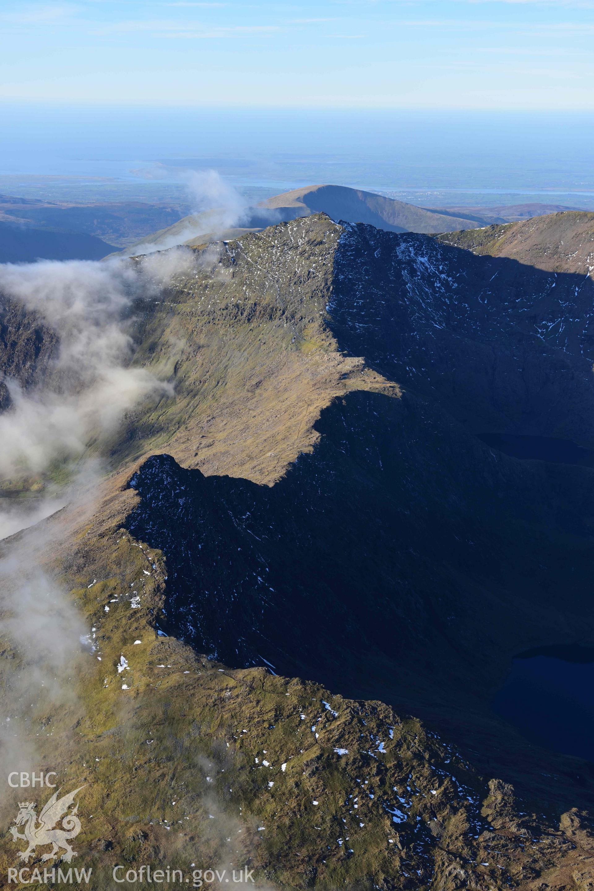 Oblique aerial photograph of Snowdon mountain landscape with Crib Goch ridge, taken from the east during the Royal Commission’s programme of archaeological aerial reconnaissance by Toby Driver on 12th January 2022