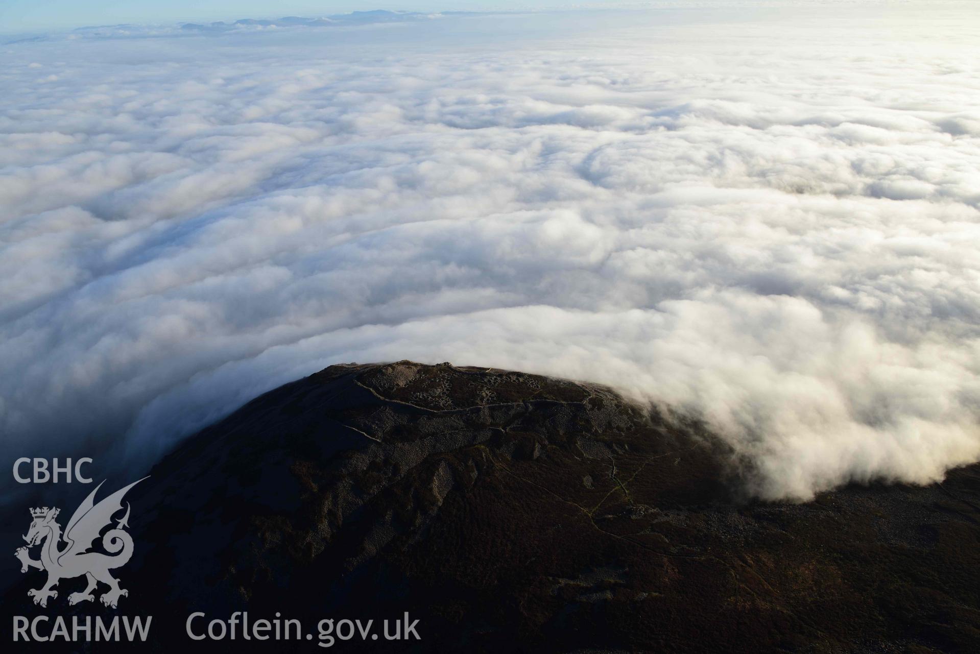 Oblique aerial photograph of Tre'r Ceiri, with cloud inversion, taken during the Royal Commission