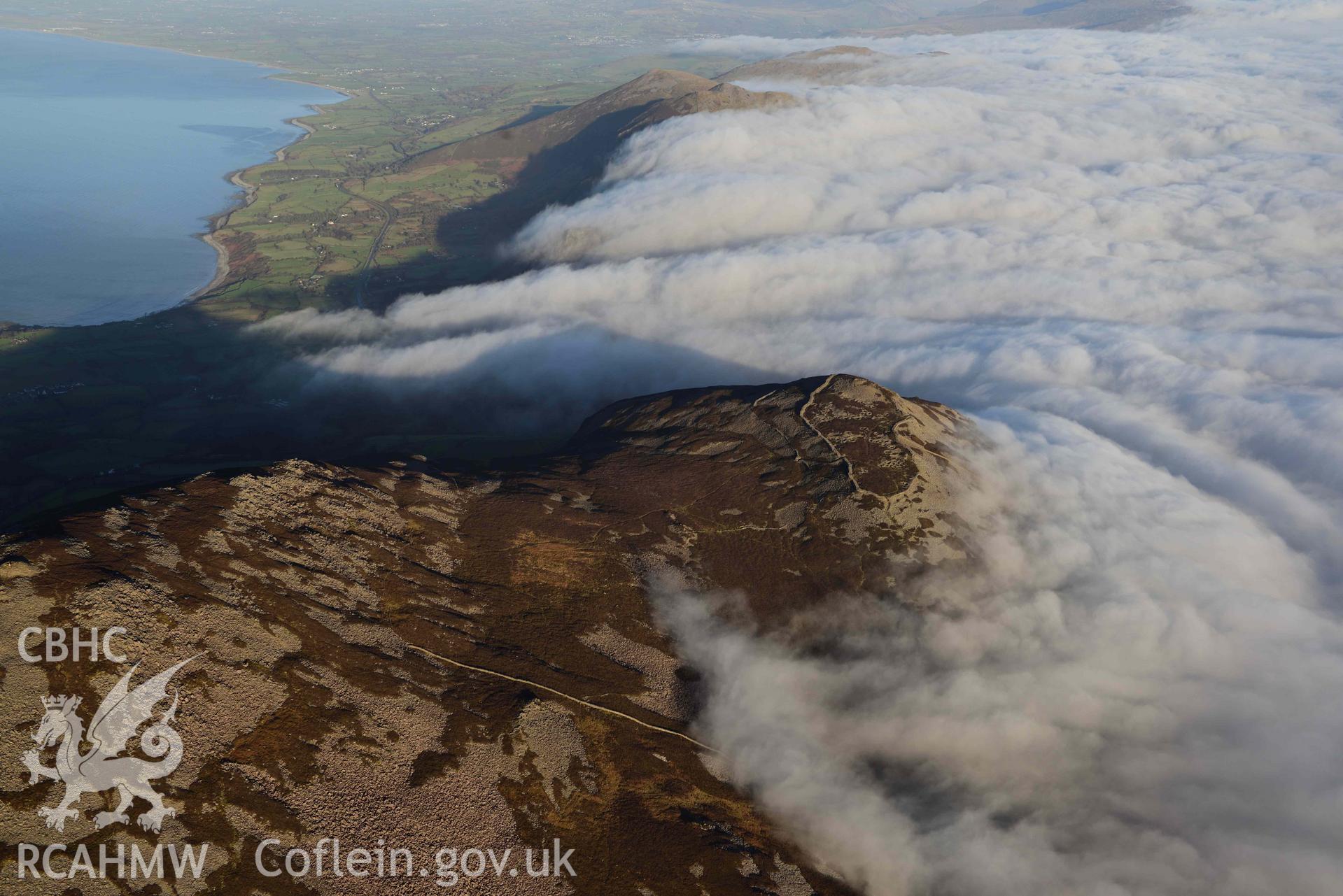 Oblique aerial photograph of Tre'r Ceiri, with cloud inversion, taken during the Royal Commission