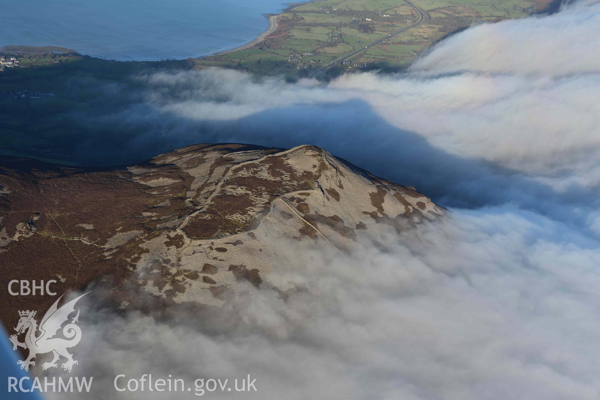 Oblique aerial photograph of Tre'r Ceiri, with cloud inversion, taken during the Royal Commission