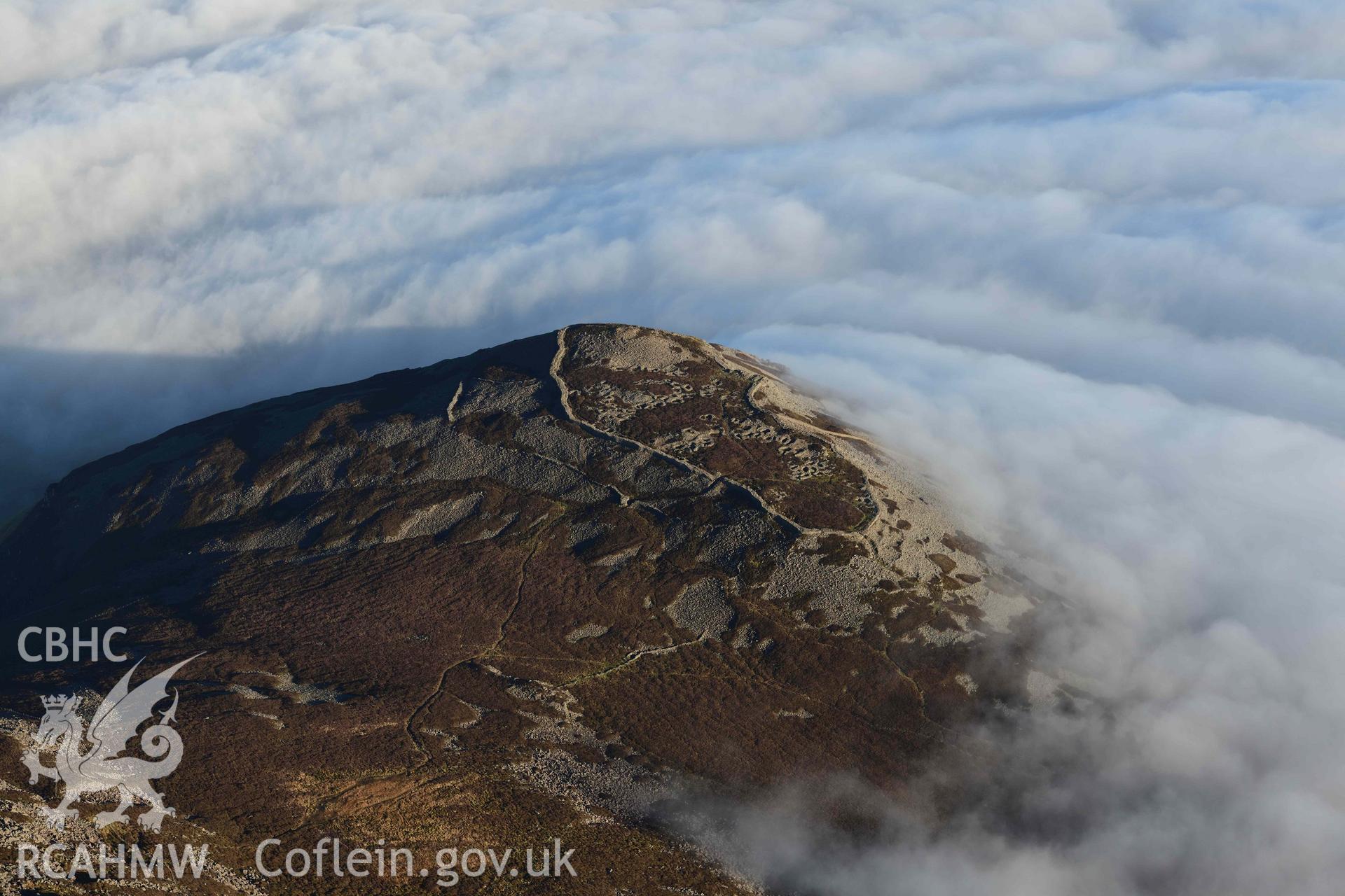 Oblique aerial photograph of Tre'r Ceiri, with cloud inversion, taken during the Royal Commission