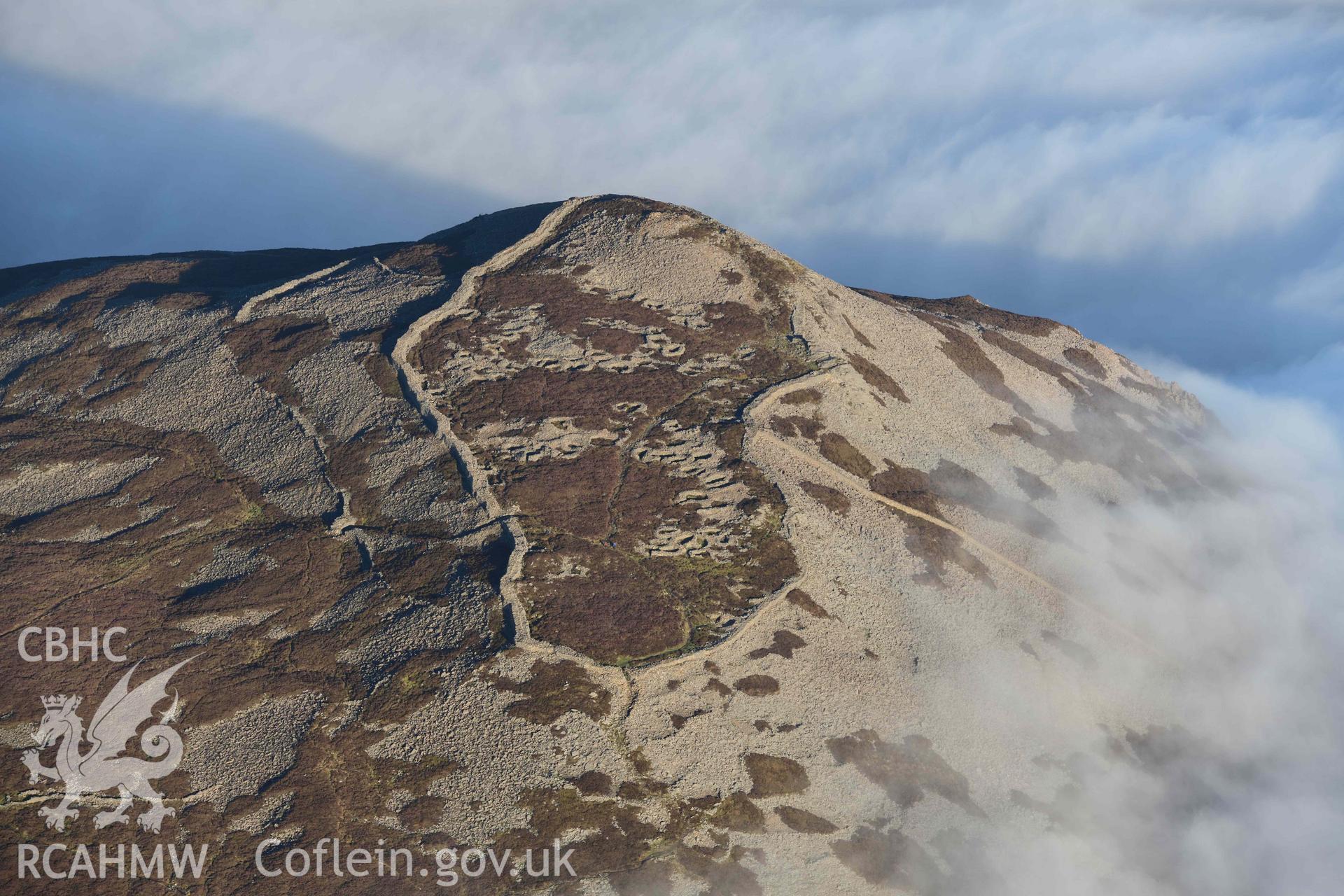 Oblique aerial photograph of Tre'r Ceiri, with cloud inversion, taken during the Royal Commission